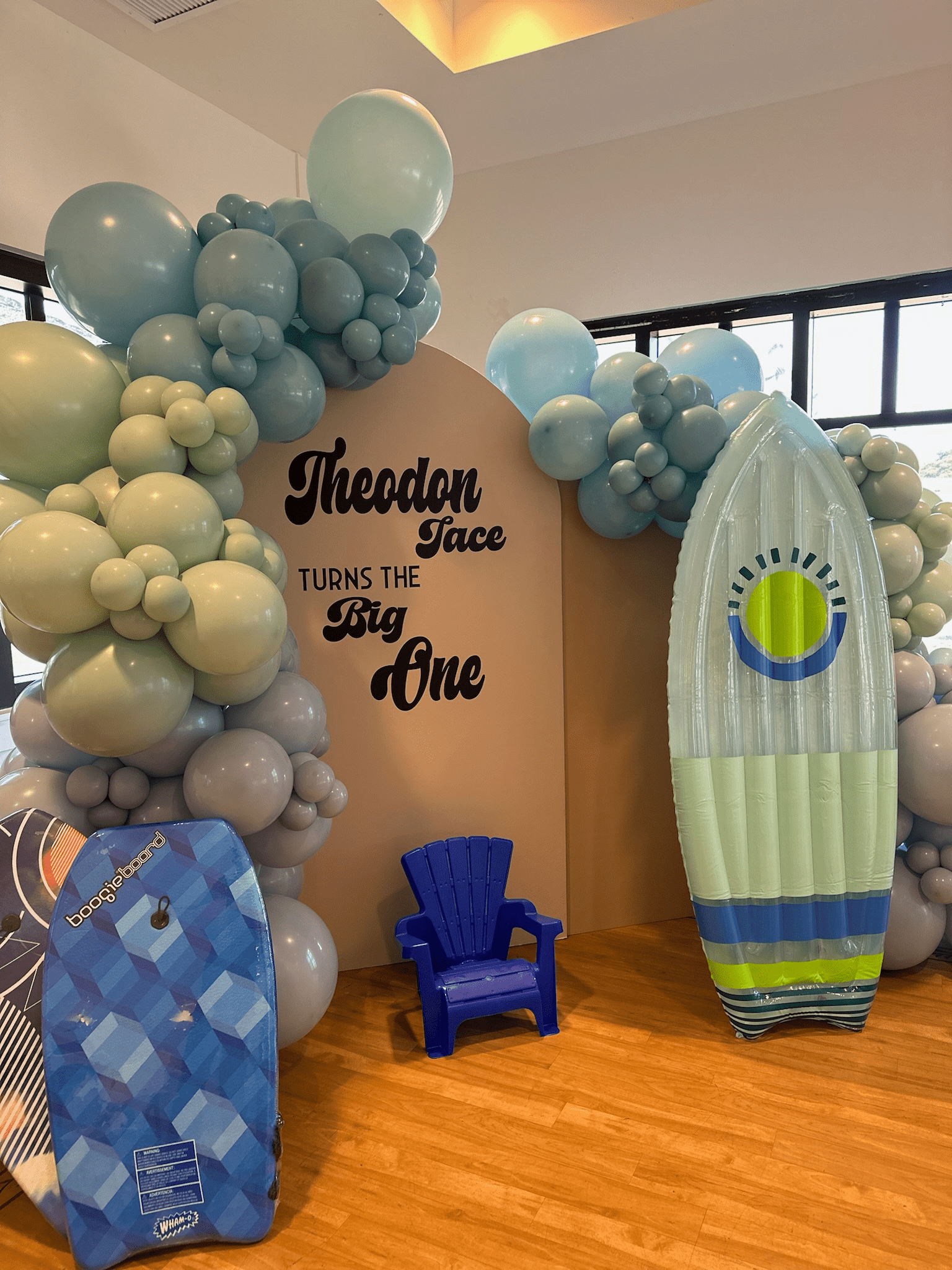 A room decorated with balloons and a surfboard.