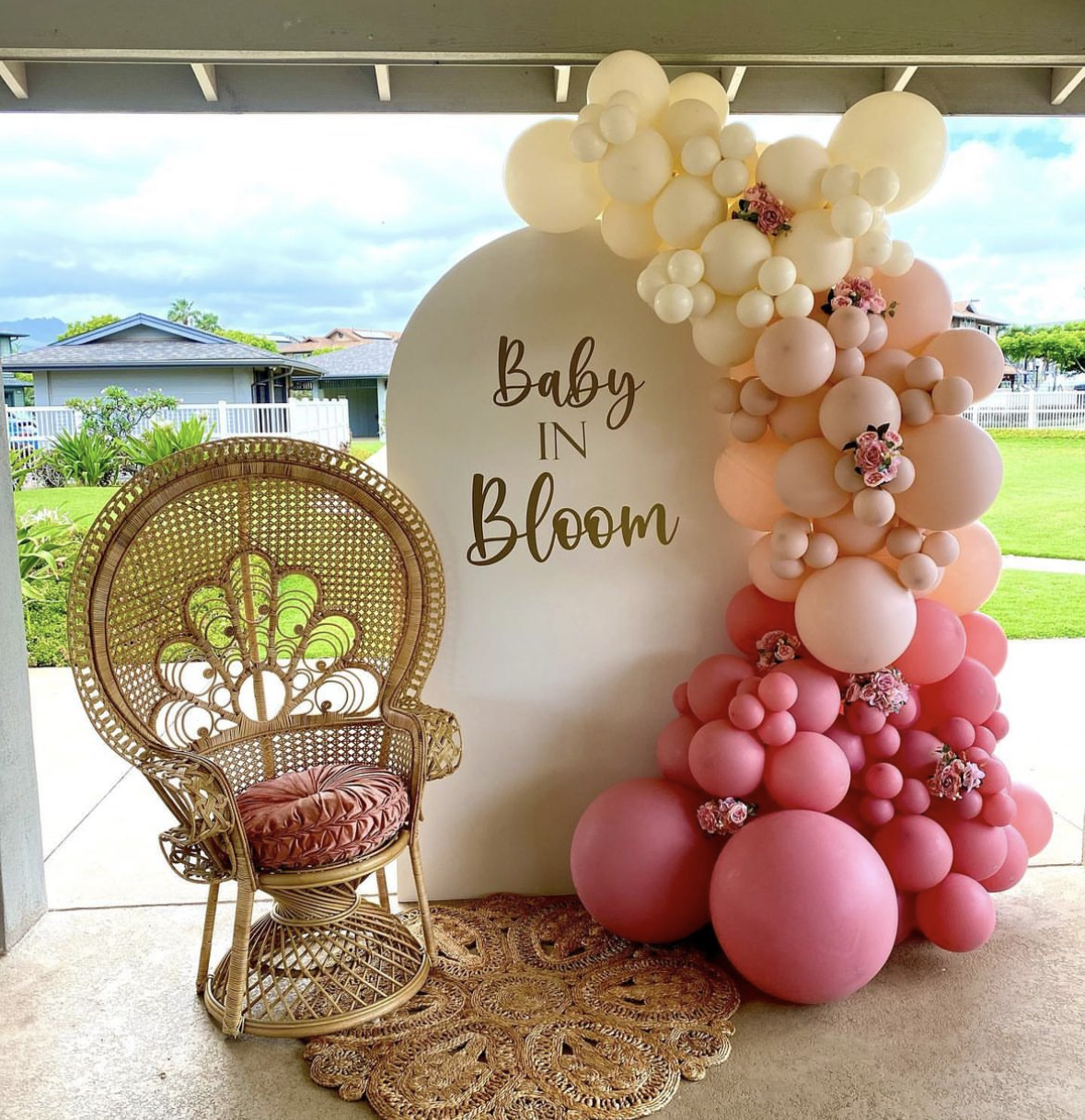 A wicker chair is sitting in front of a sign that says baby in bloom