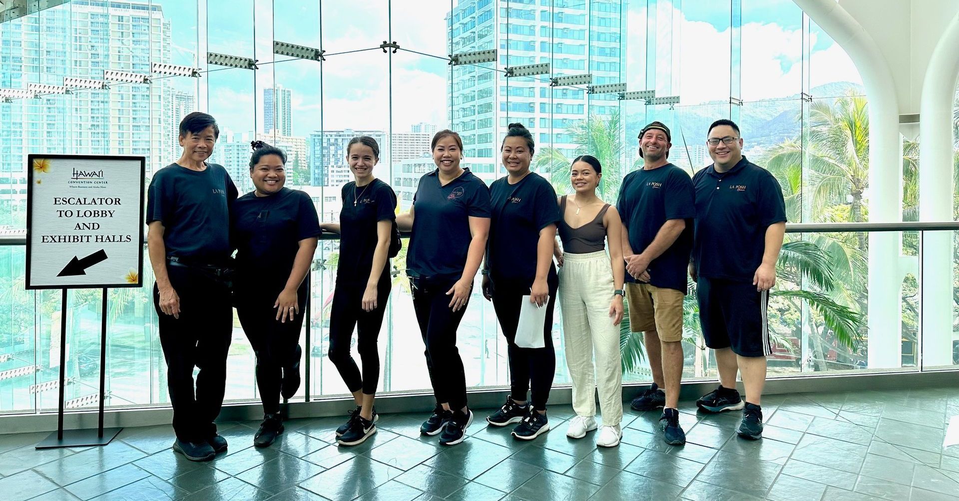 A group of people are posing for a picture in front of a large window.