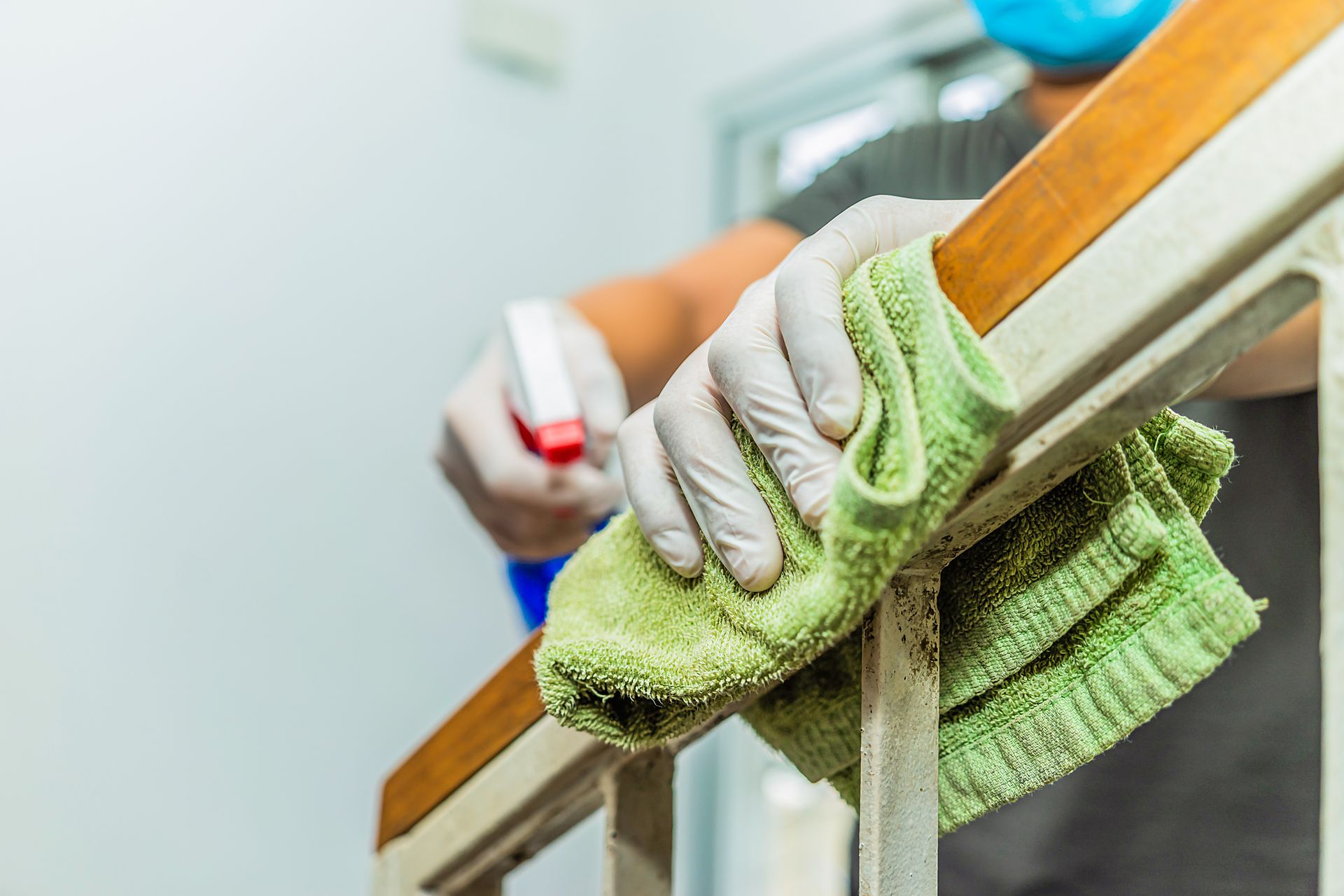 Person in orange gloves cleaning a window with spray bottle and squeegee.