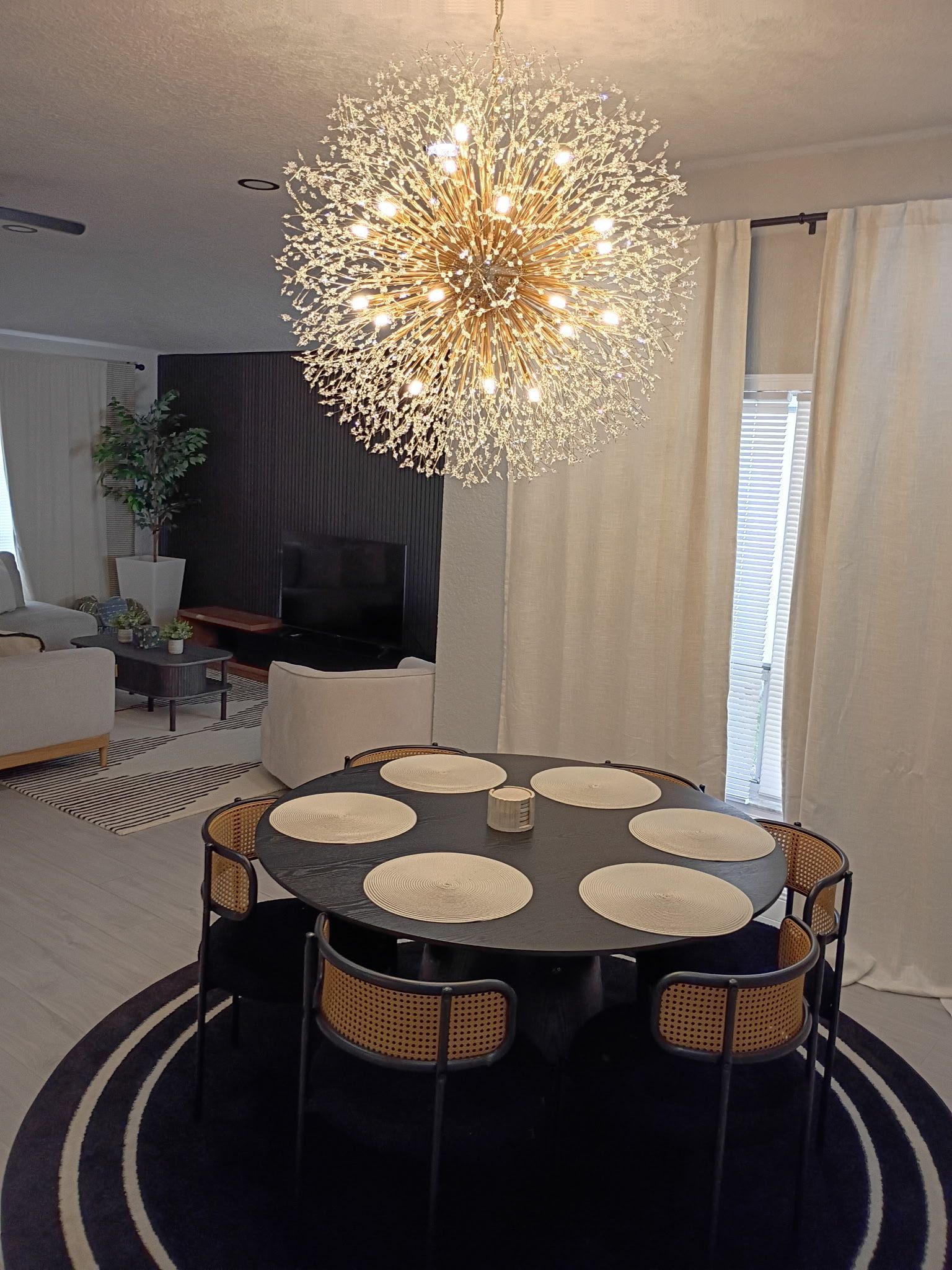 Dining room with round table, chairs, and large chandelier.