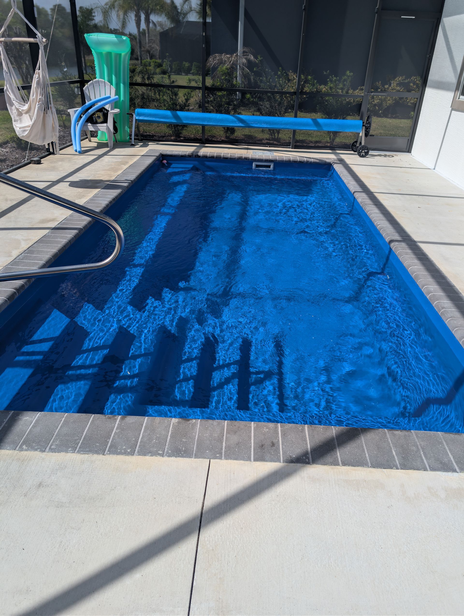 Backyard swimming pool with bright blue water and a safety fence in the background
