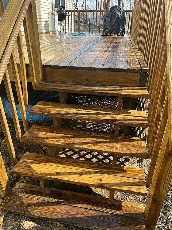 Wooden outdoor staircase leading to a deck, with wet wood and visible latticework.