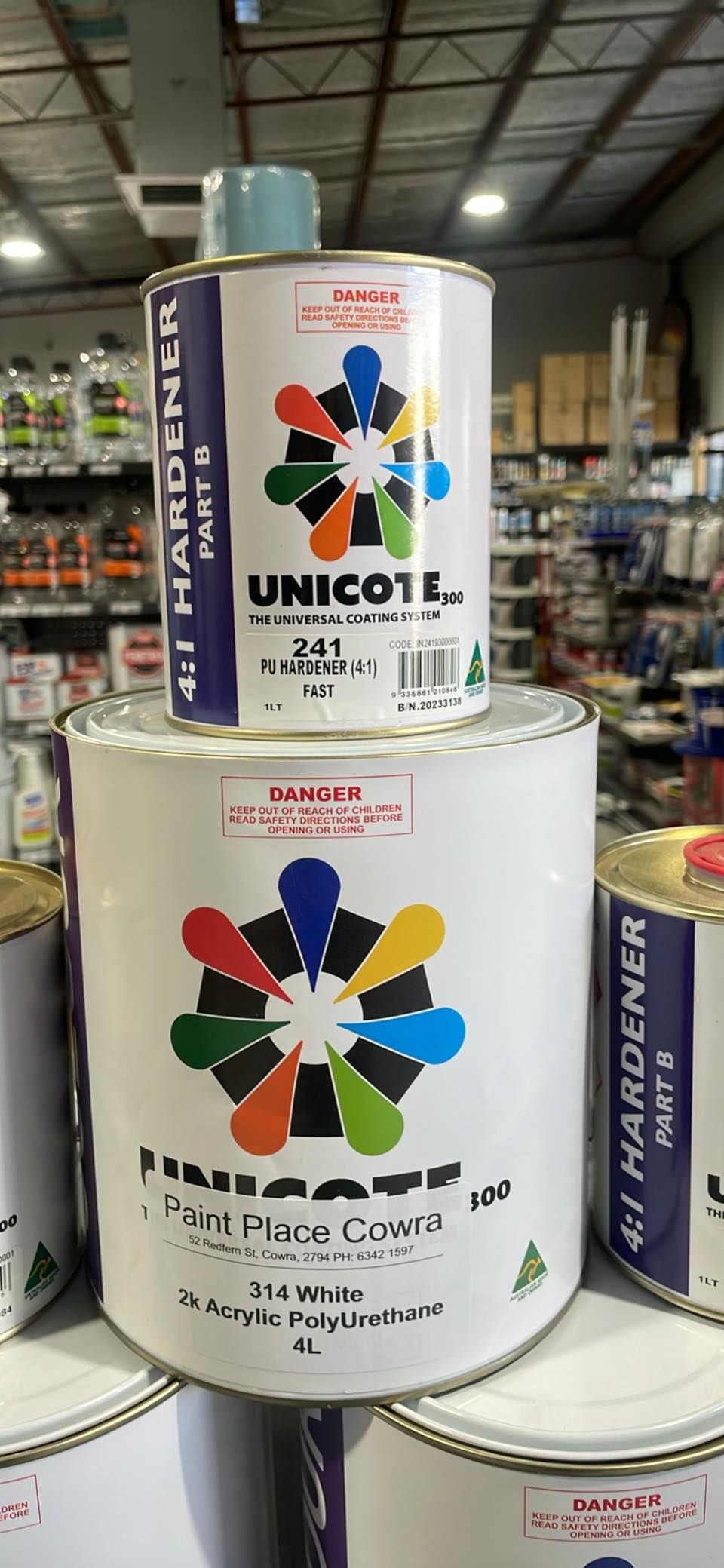 Paint Cans Stacked in a Warehouse, Labeled Unicote and Puro Placa Crown — Paint Place Cowra in Forbes, NSW
