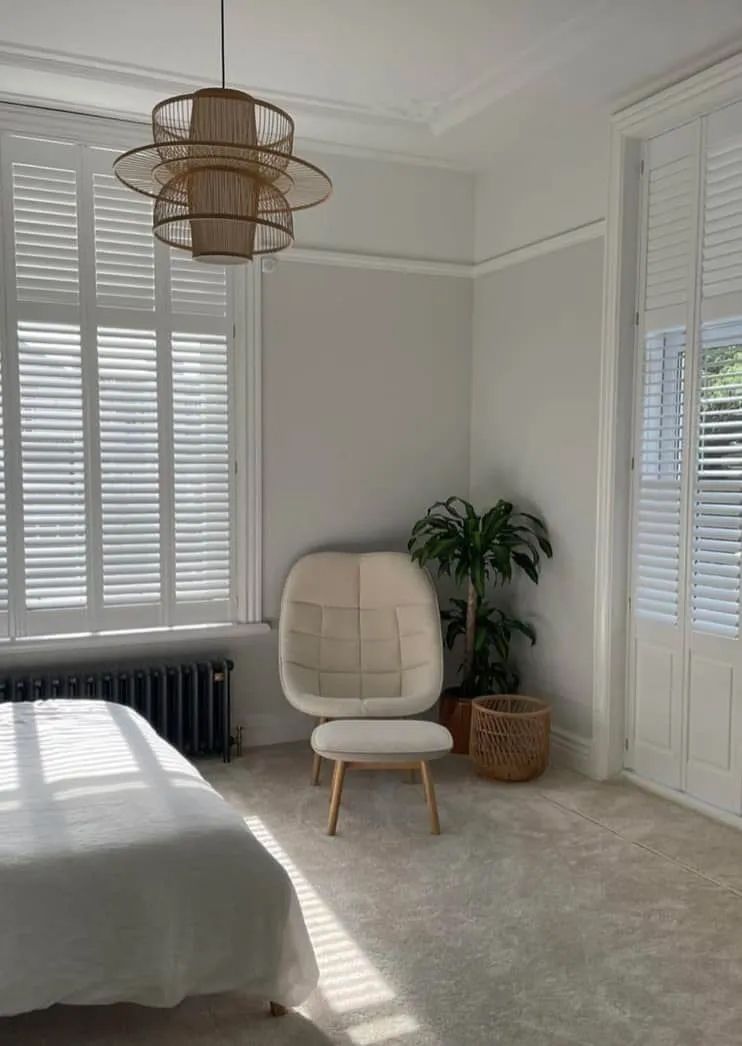 Bright Bedroom With White Chair, Plant, Bed, and Large Shuttered Windows — Paint Place Cowra in Cowra, NSW