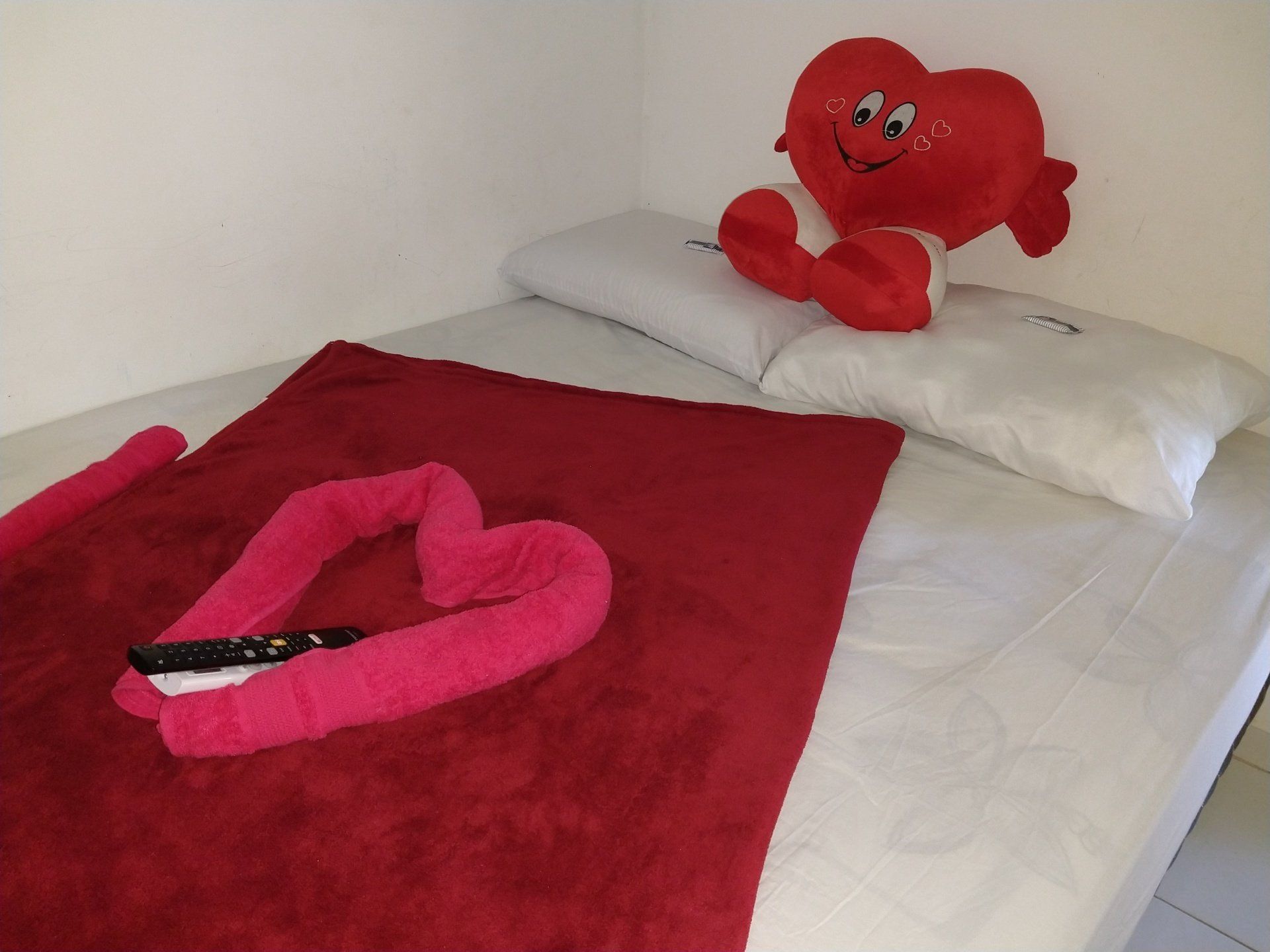 Uma cama com uma toalha em formato de coração e um coração de pelúcia sobre ela