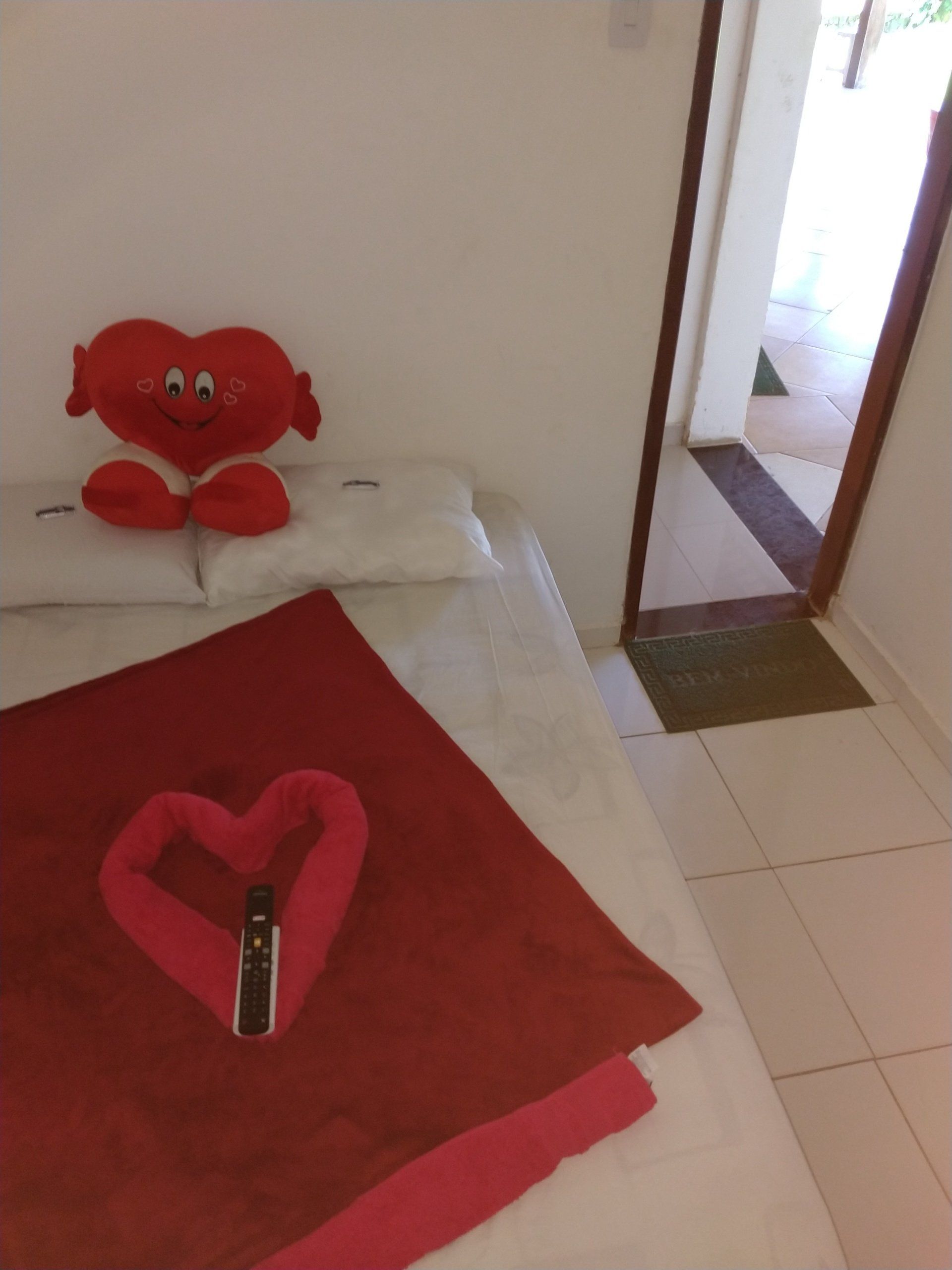 Uma cama com toalhas vermelhas e um coração de pelúcia