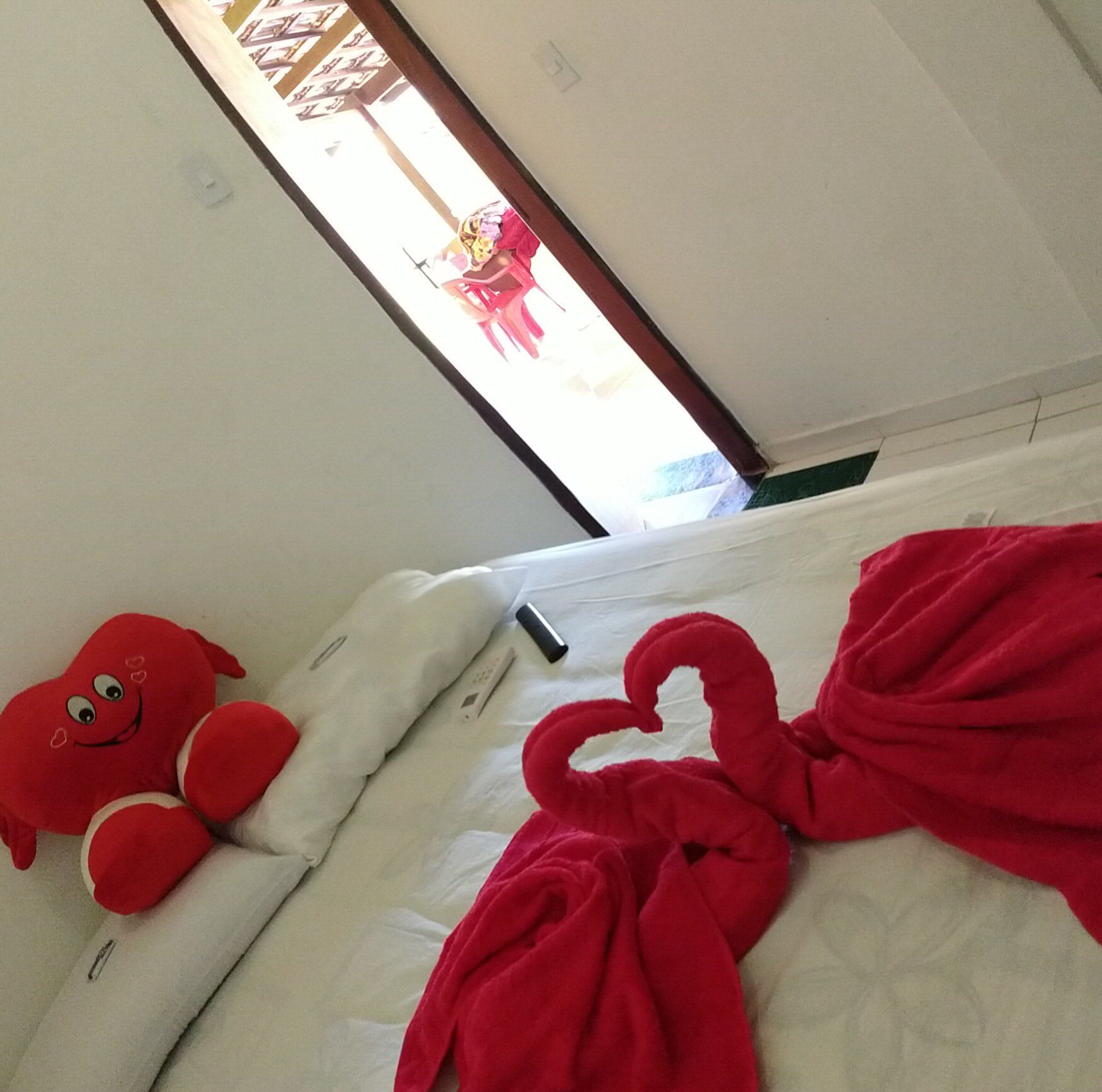 Uma cama com toalhas vermelhas e um bicho de pelúcia sobre ela