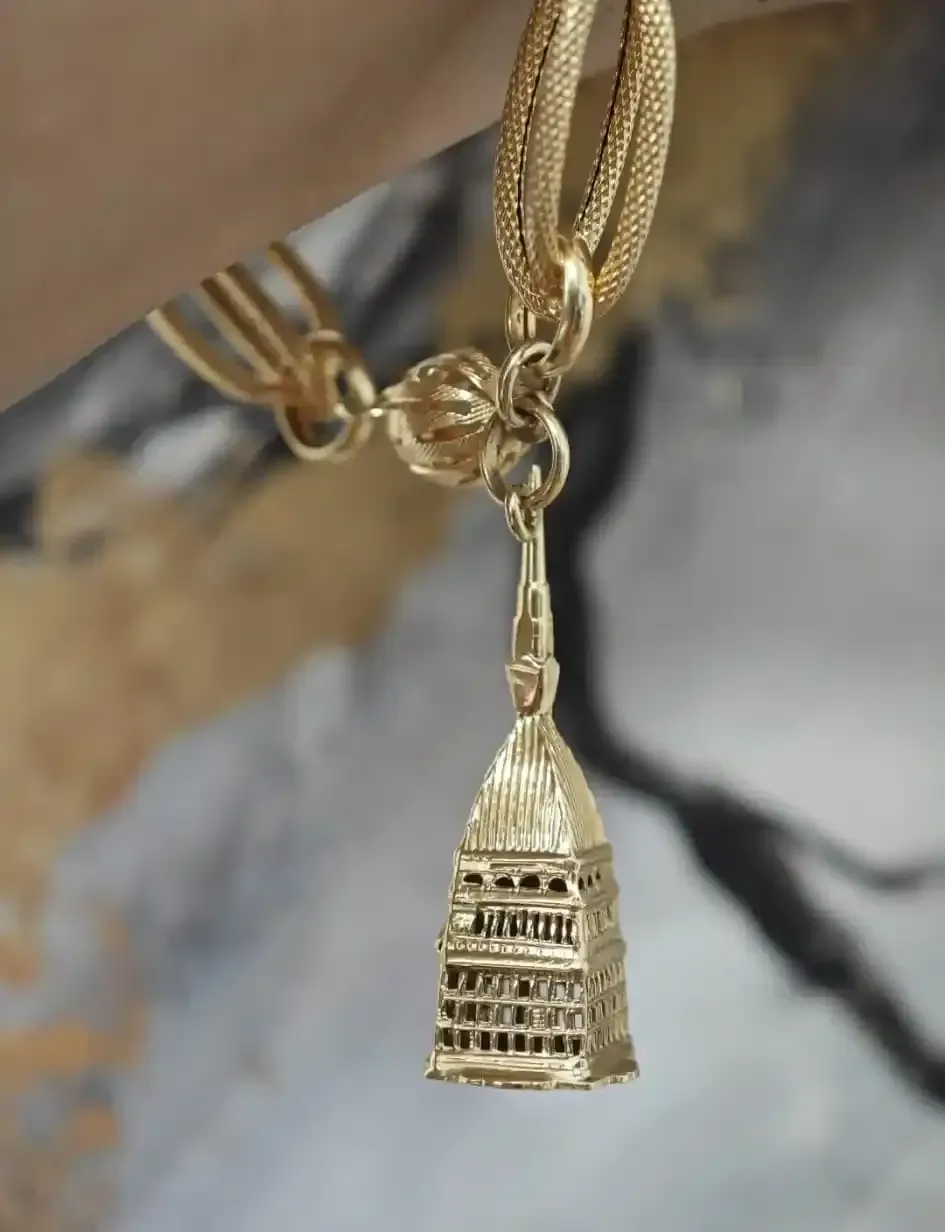 Collana con pendente in oro e un piccolo ciondolo decorato a forma di tempio su una catenina