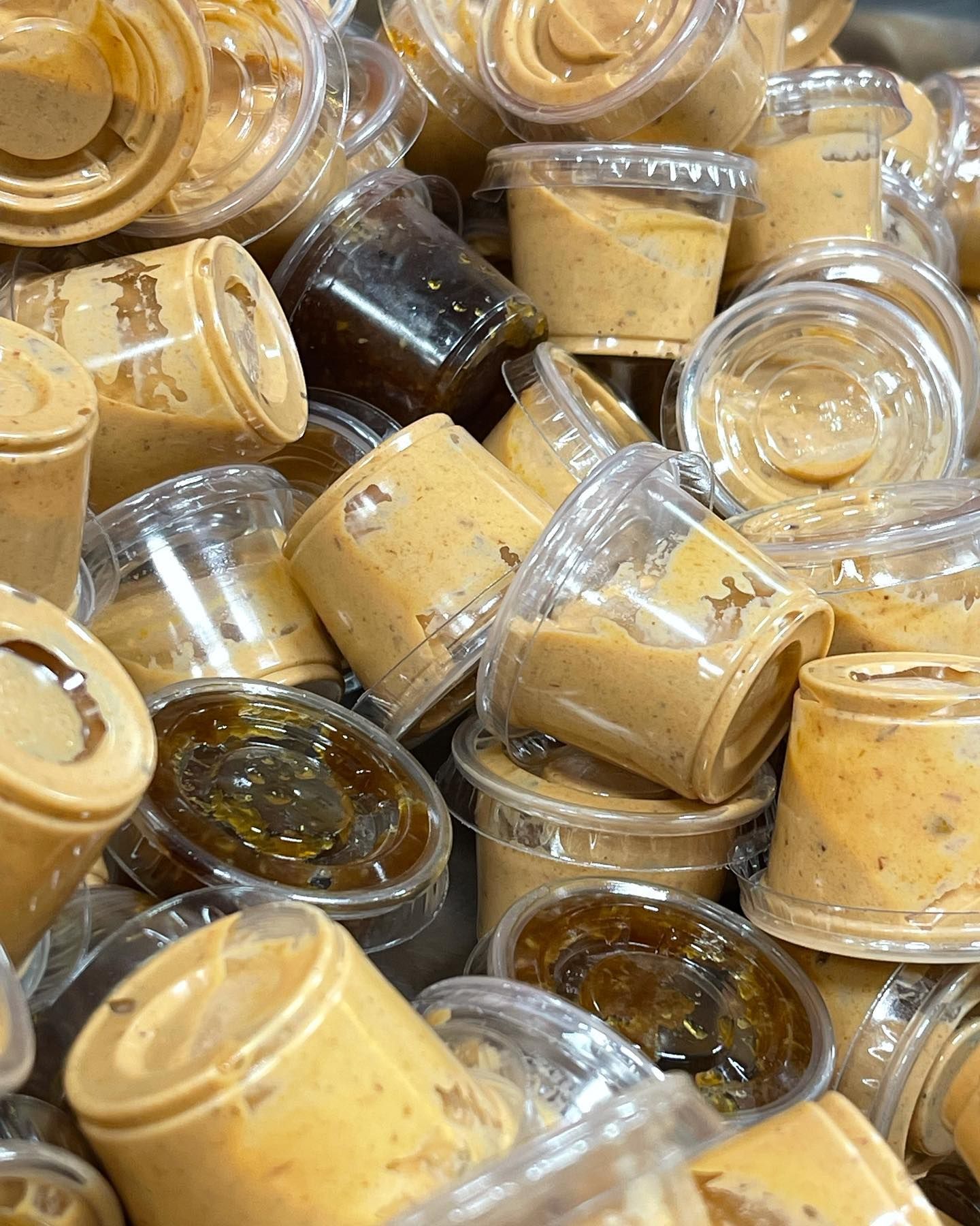 A pile of plastic cups filled with peanut butter and sauce.