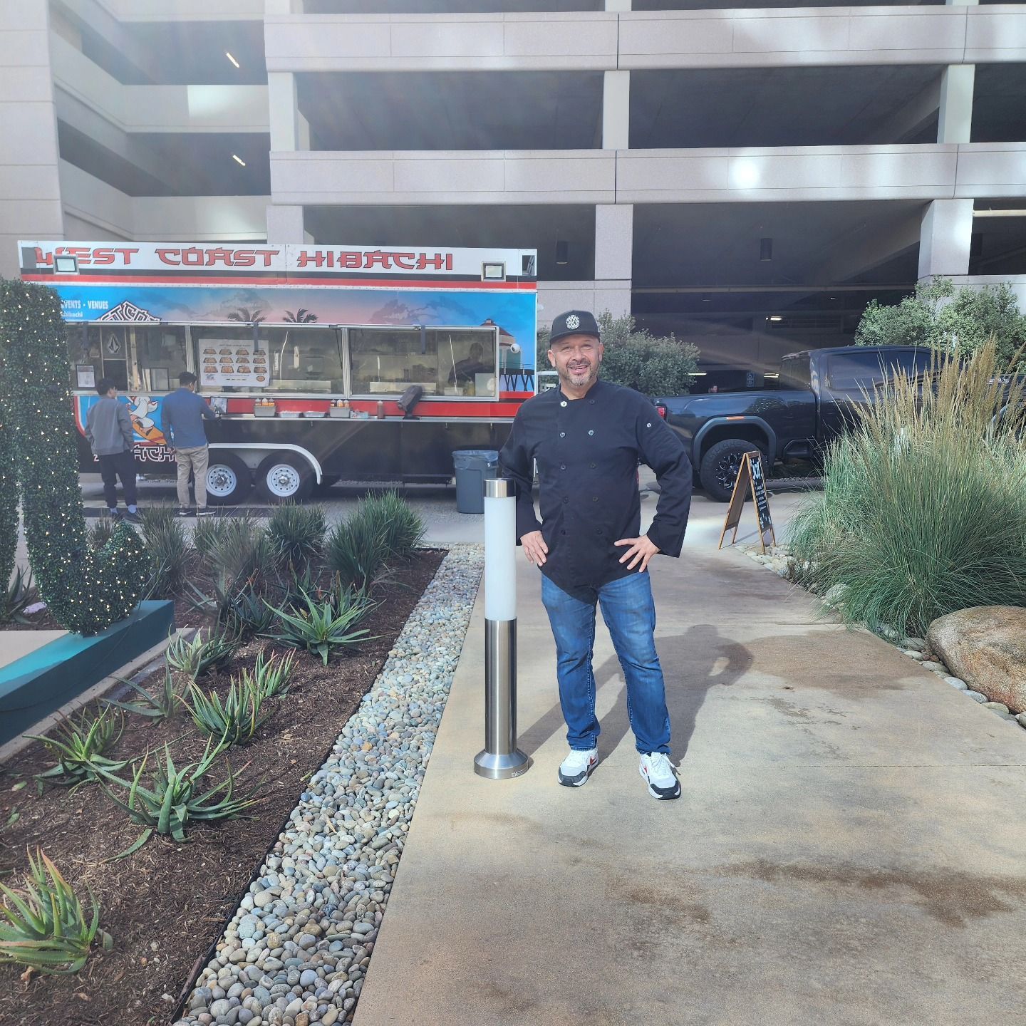 A man stands in front of a food truck that says first coast hibachi