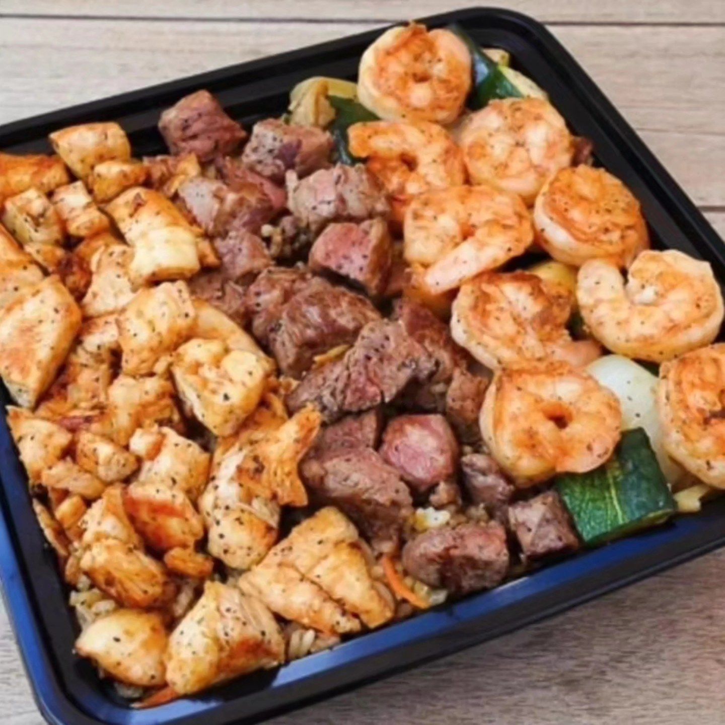 A tray filled with meat and shrimp on a table