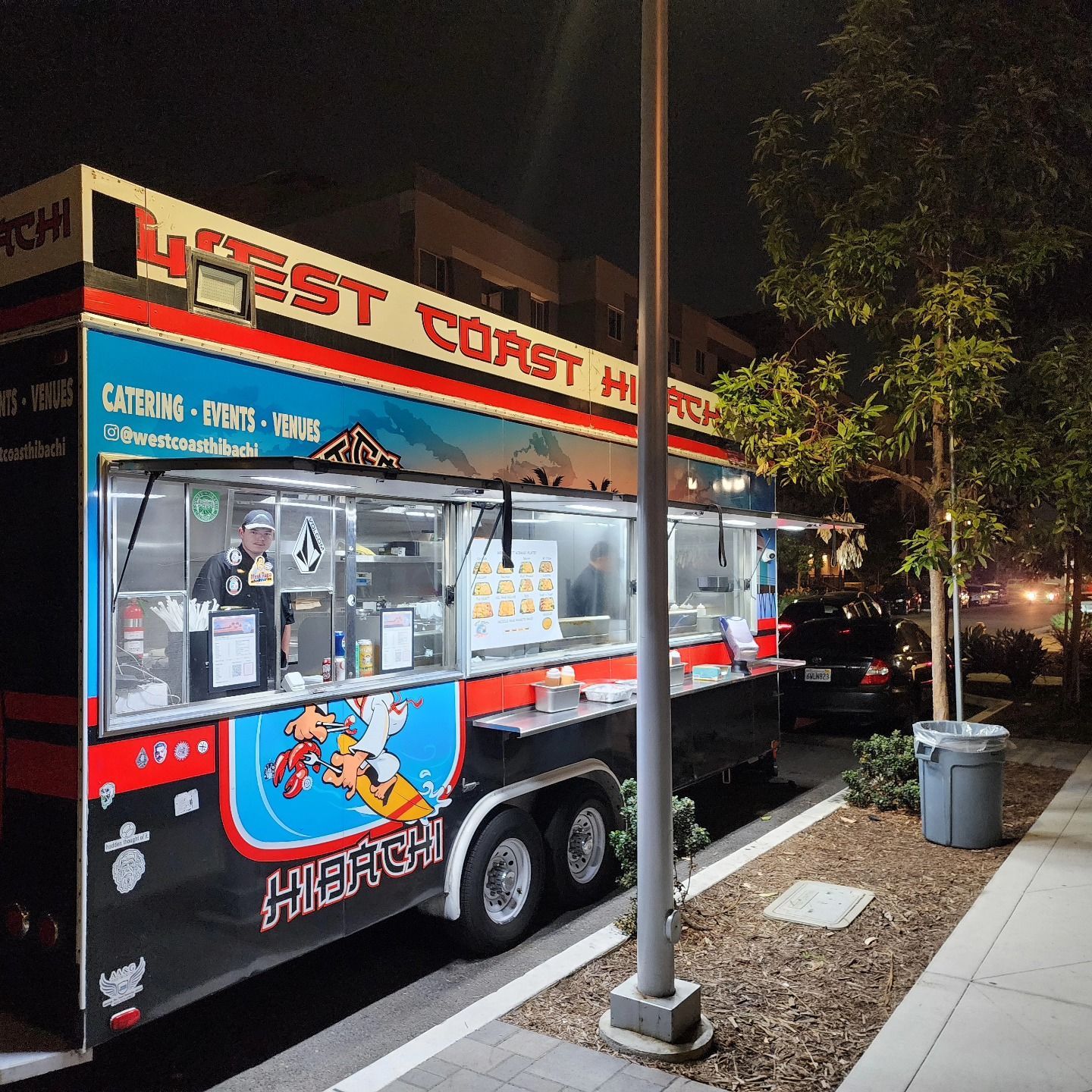 A food truck is parked on the side of the road at night