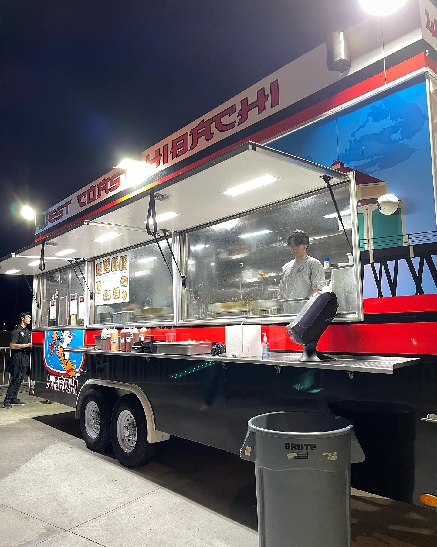 A food truck is parked on the side of the road at night.