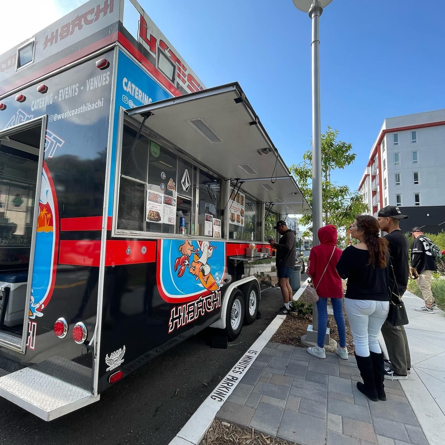 A group of people are standing in front of a food truck that says hibachi