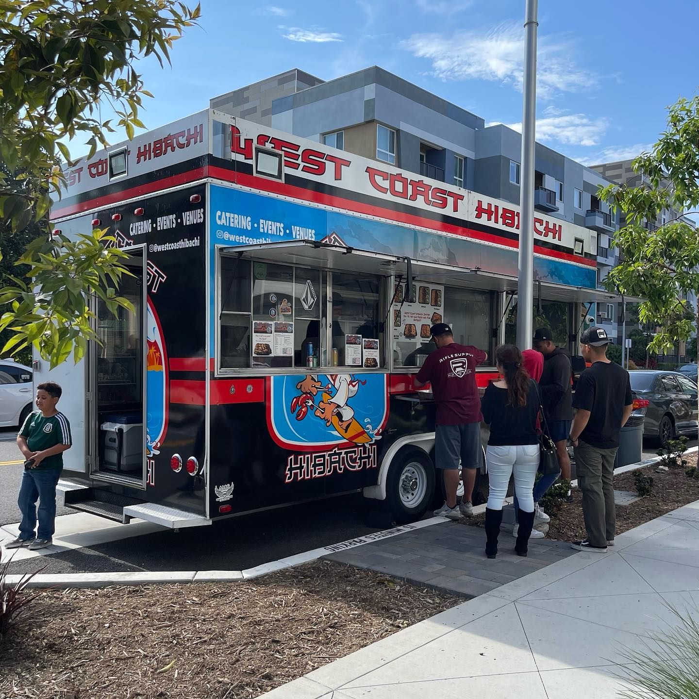 A group of people are standing in front of a food truck.
