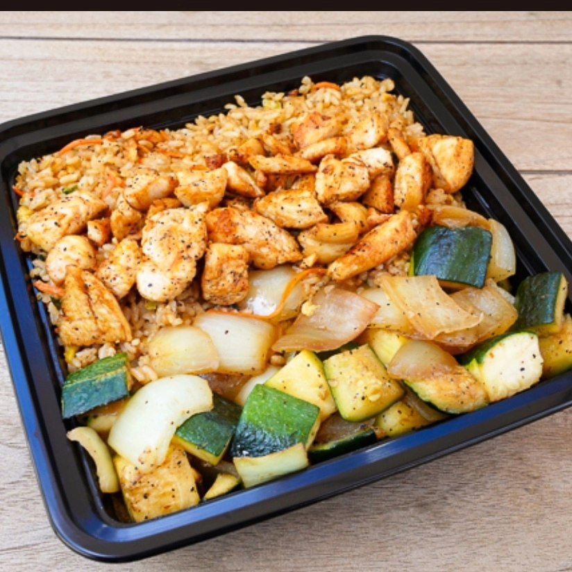 A black container filled with chicken rice and vegetables