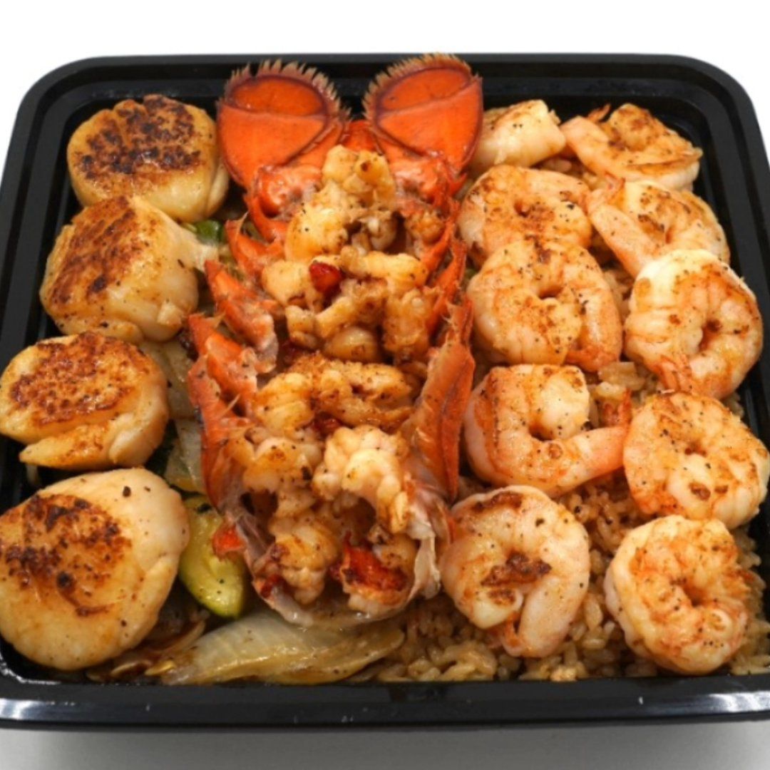 A black container filled with shrimp scallops and rice