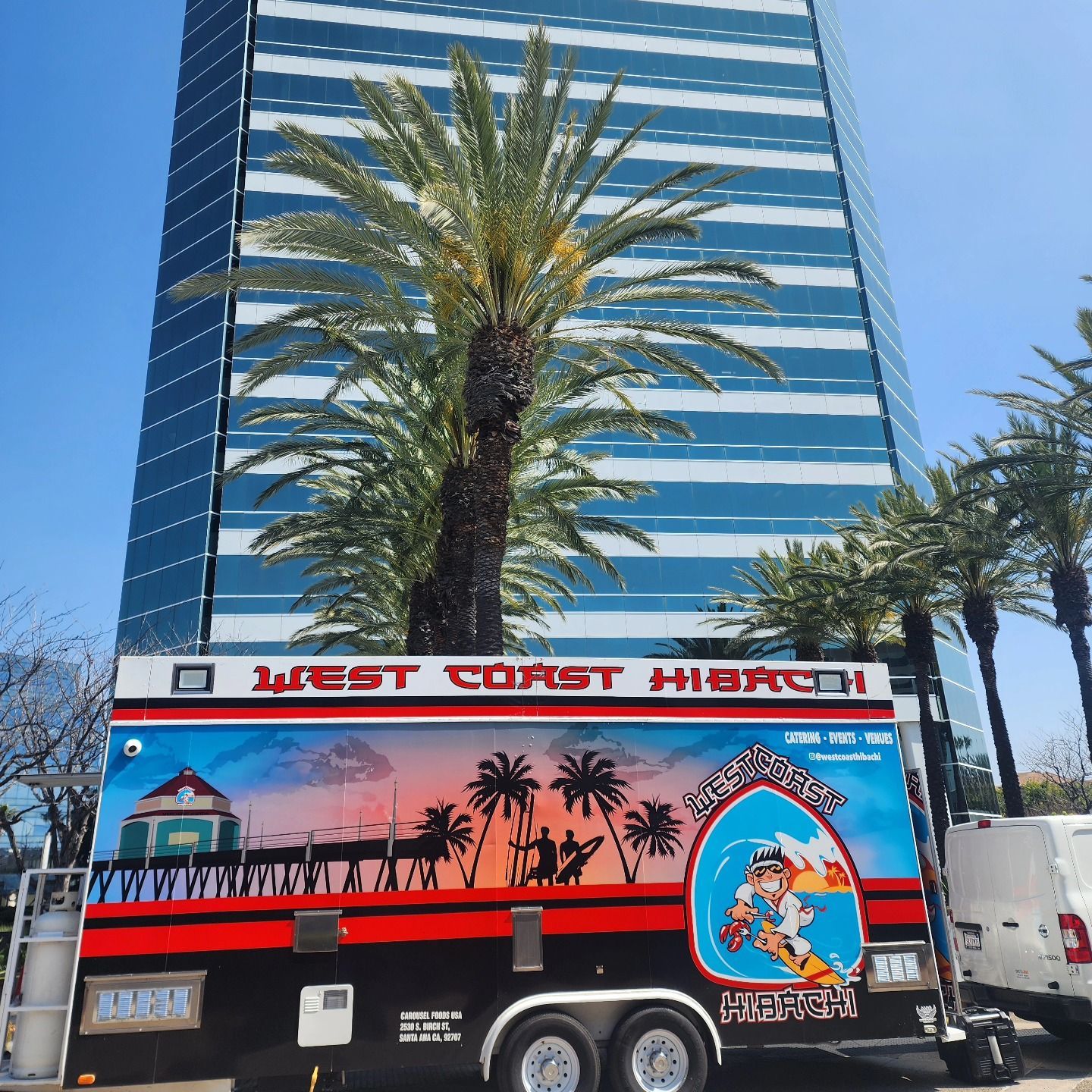 A west coast highway food truck is parked in front of a tall building
