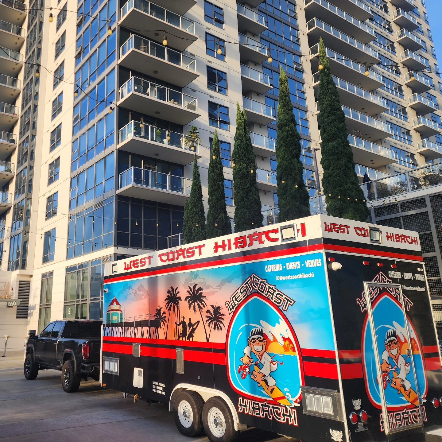 A food truck is parked in front of a tall building