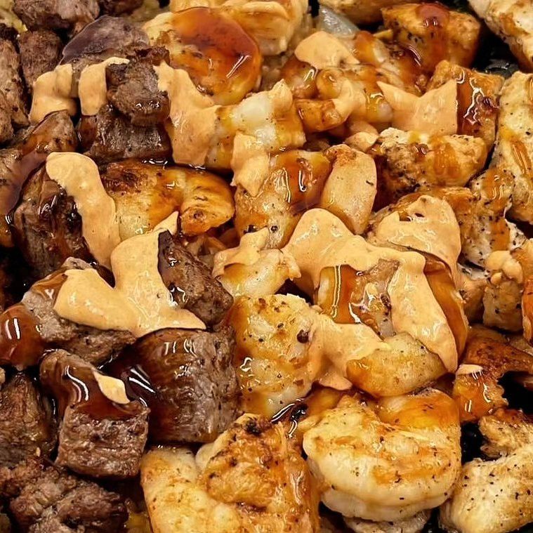 A close up of a plate of food with meat , shrimp , and sauce.