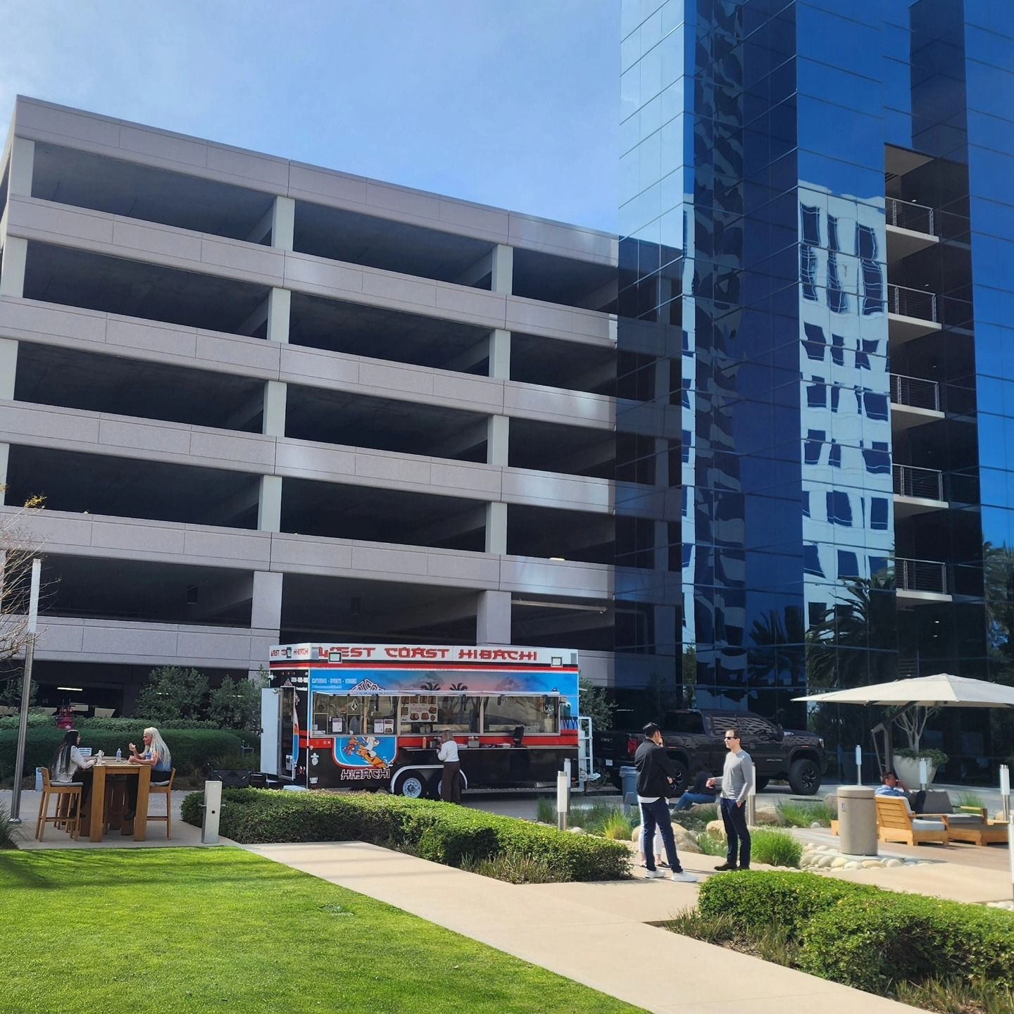 A food truck is parked in front of a parking garage