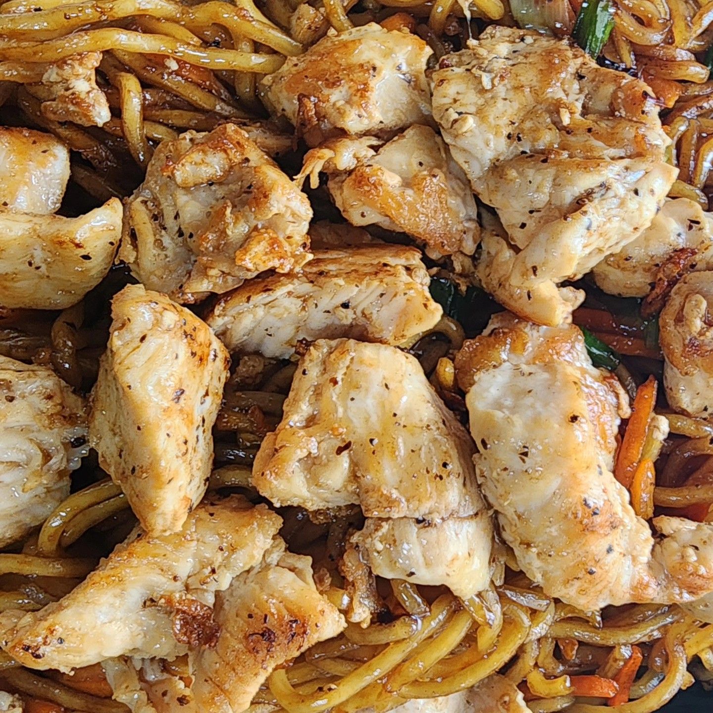 A close up of a plate of food with noodles and chicken.