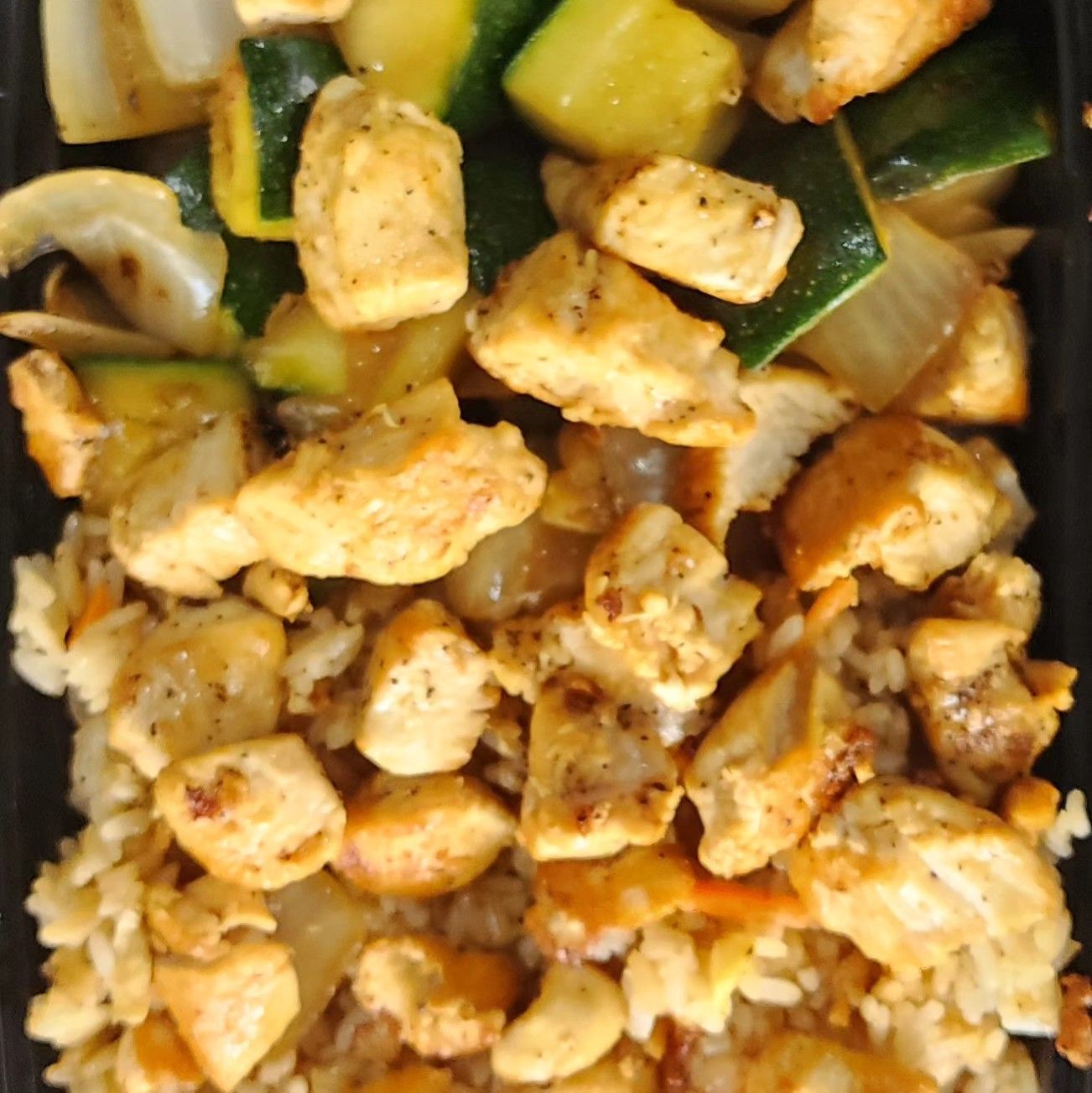 A black container filled with chicken and vegetables
