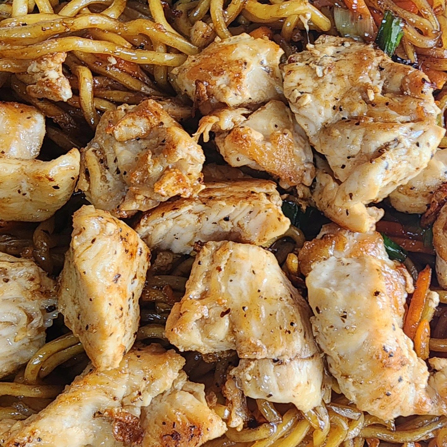 A close up of a plate of food with noodles and chicken.
