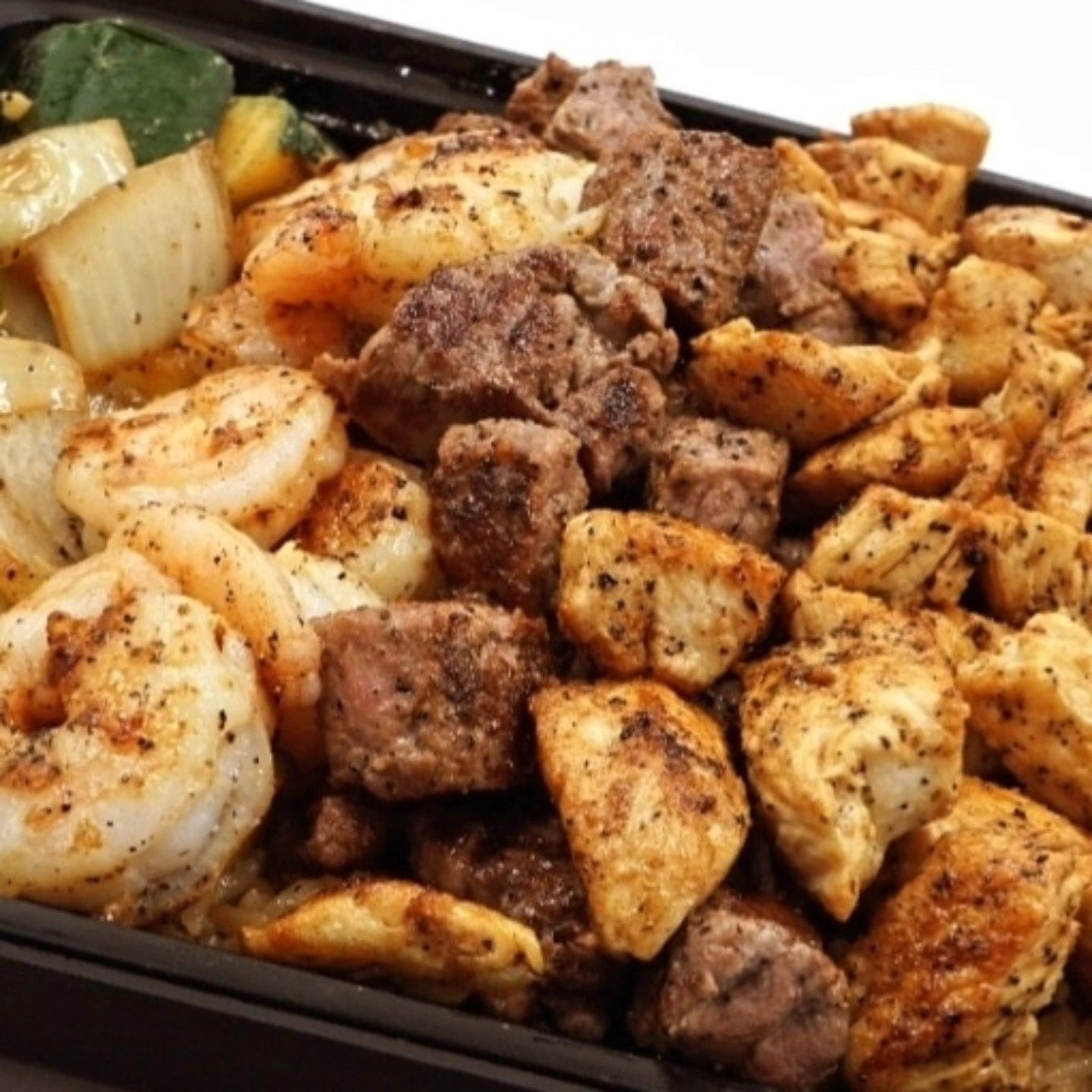 A close up of a tray of meat and shrimp