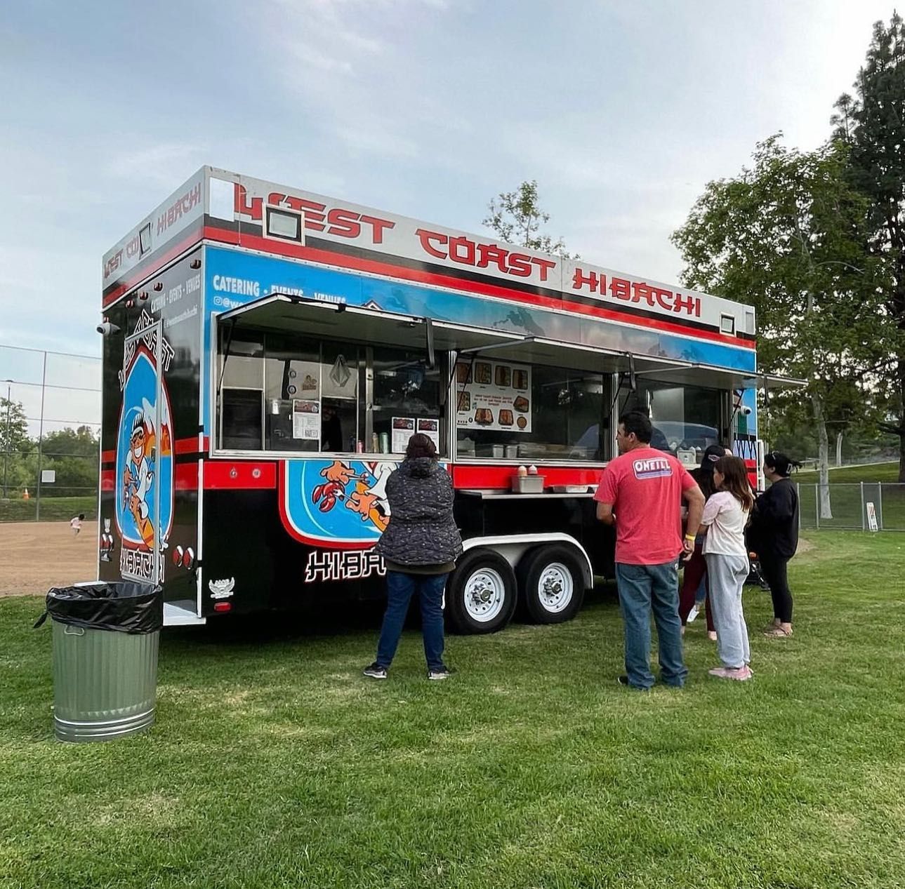 A group of people standing in front of a food truck that says latest curry