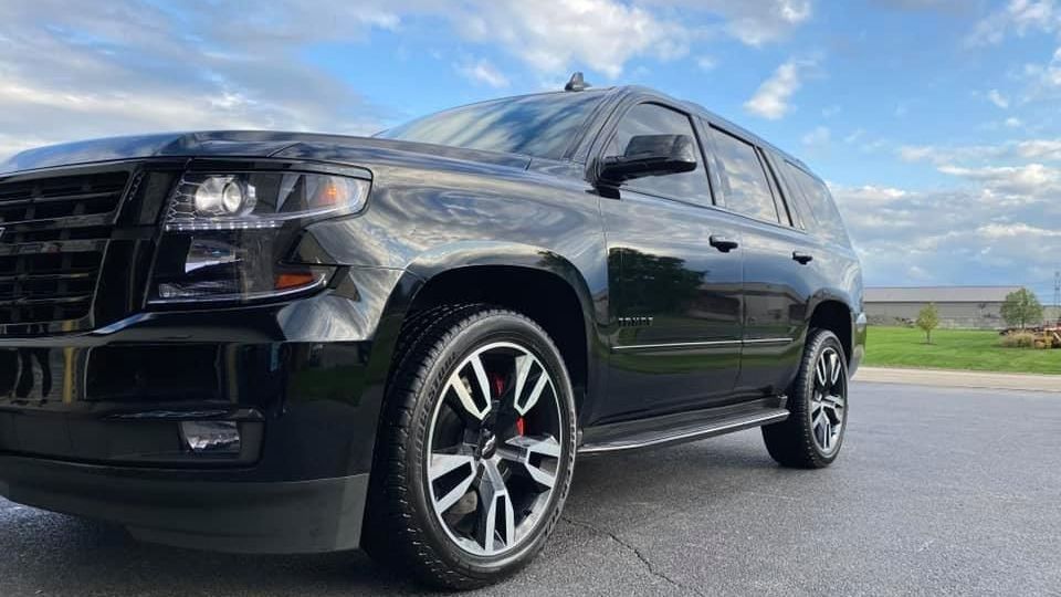 Black SUV parked on a road under a cloudy sky, front-left view with chrome wheels