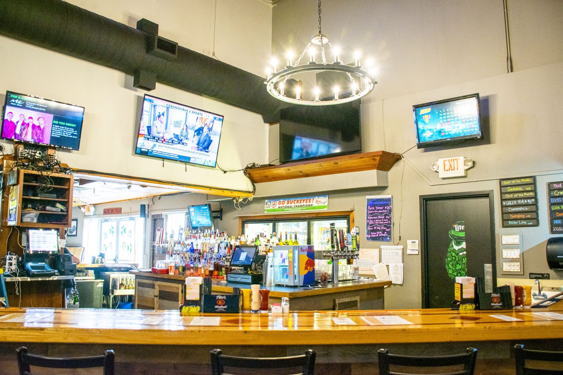 Bar with TVs, hanging lights, and a wooden counter in a casual restaurant setting