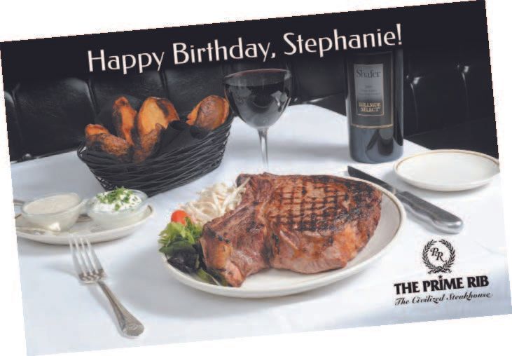 A steak dinner set for a birthday: steak, potatoes, wine, at