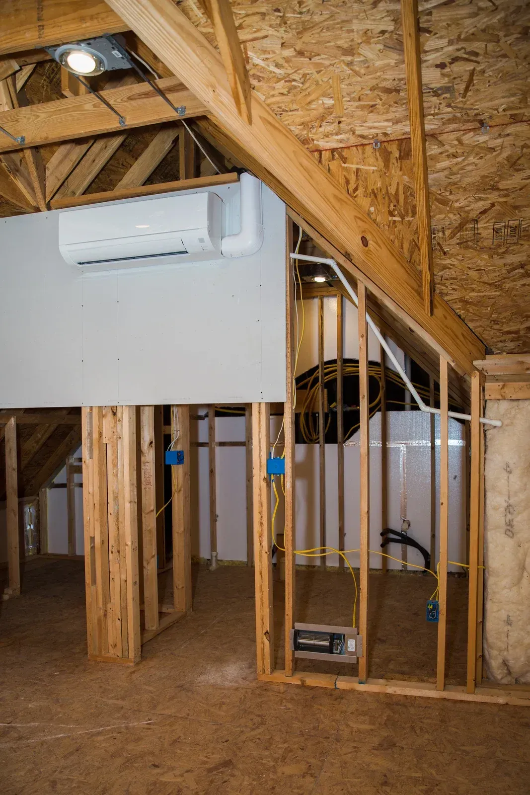 Interior construction: unfinished walls, ductwork, and an air conditioning unit.