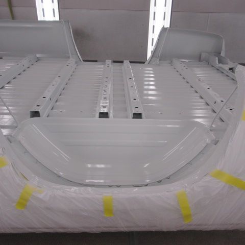White vehicle chassis being painted in a body shop.