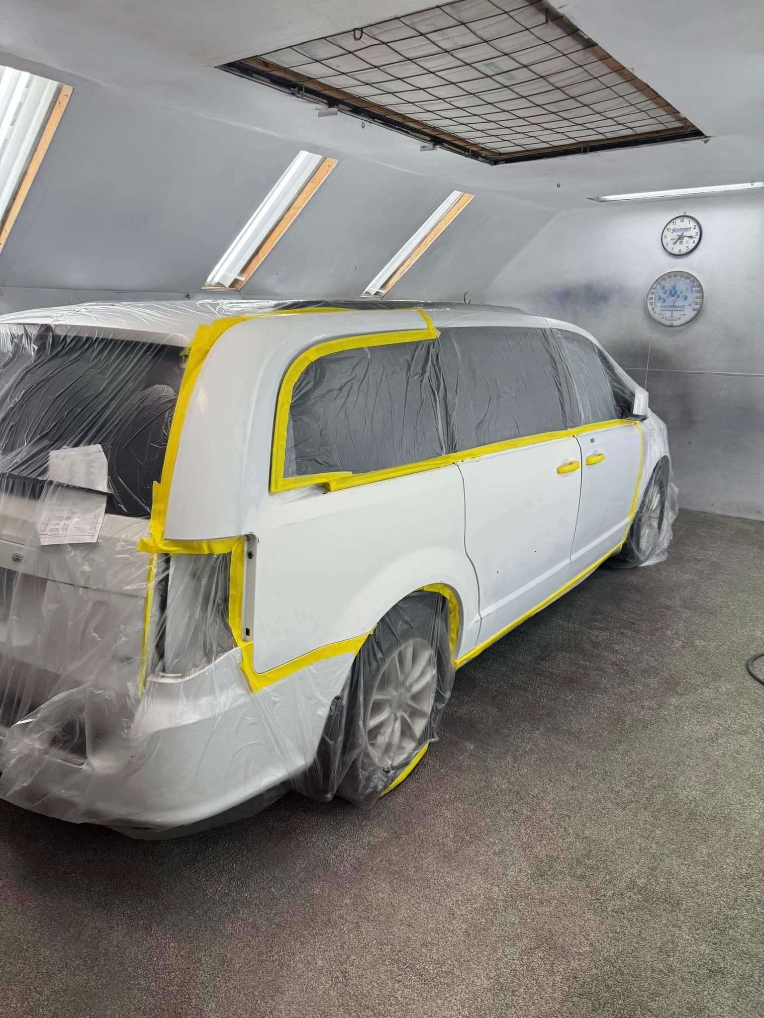 A white van is being painted in a garage.