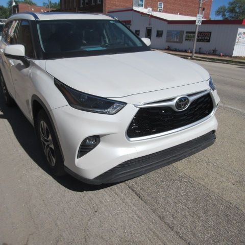 White Toyota Highlander parked on a street in front of brick buildings.
