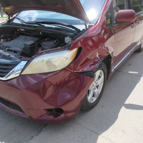 Damaged gray sedan with an open trunk and dented rear. Street scene.