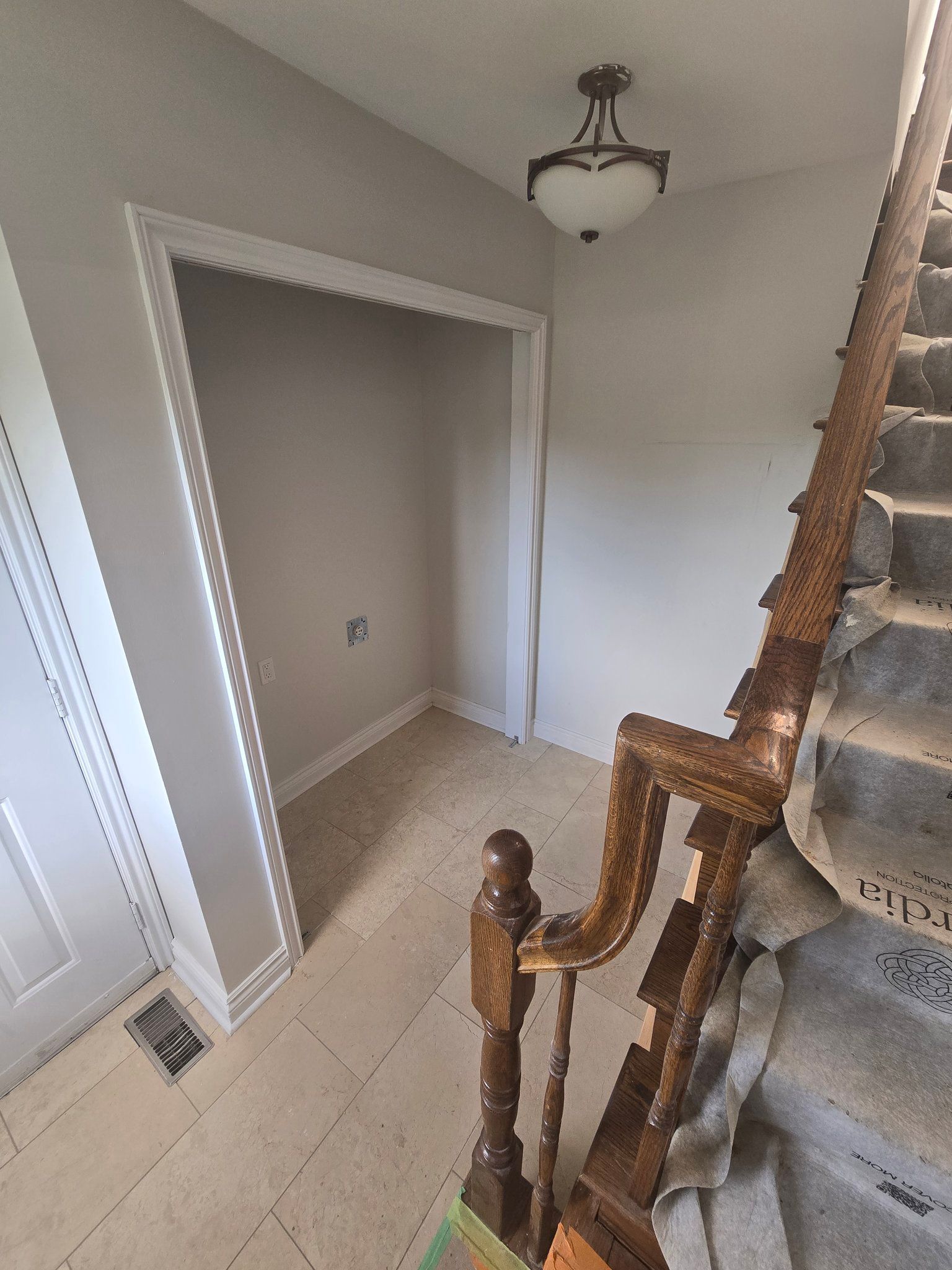 A staircase with a wooden railing and a light on the ceiling in a hallway.