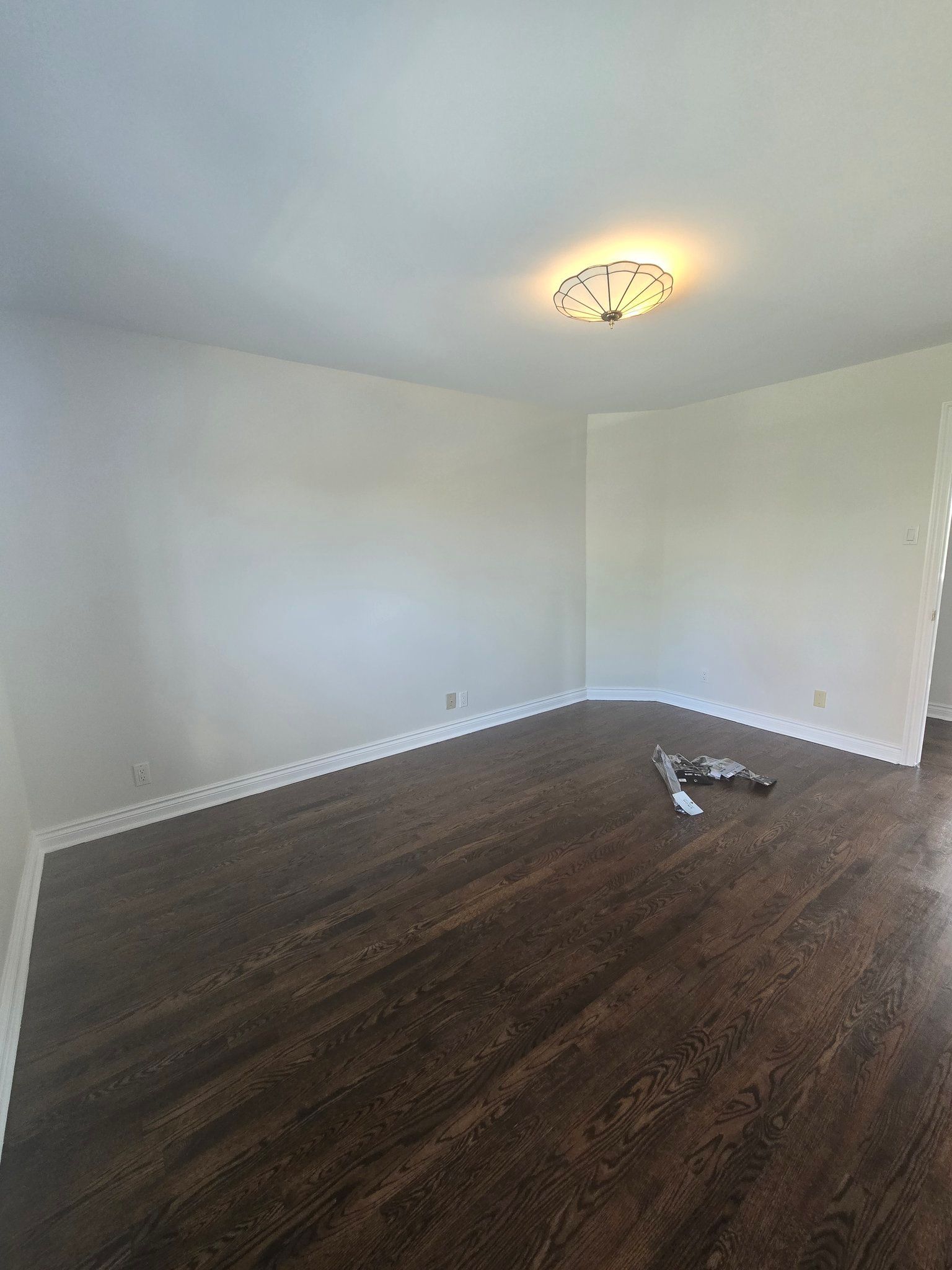 An empty living room with hardwood floors and white walls.