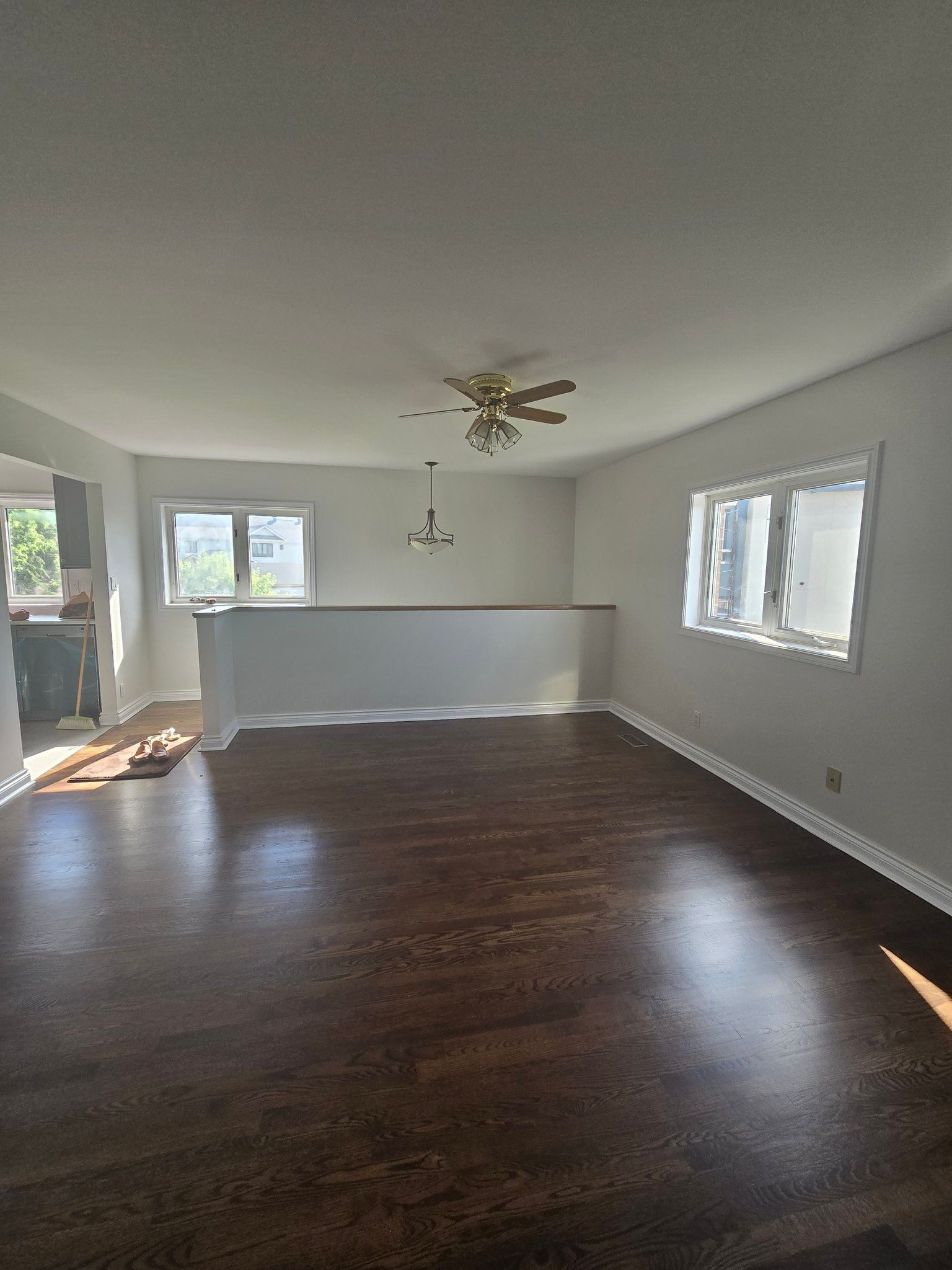 An empty living room with hardwood floors and a ceiling fan.