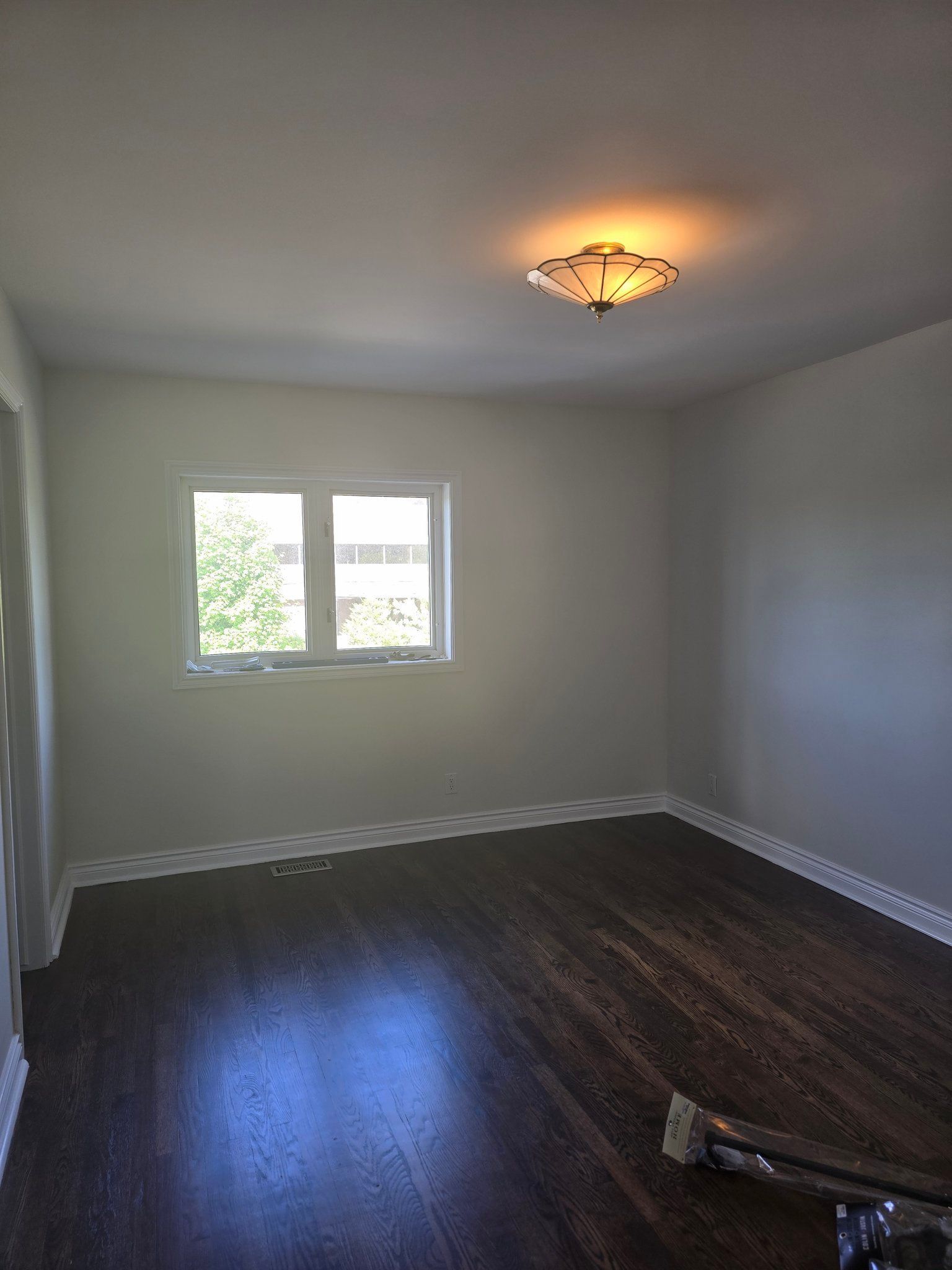 An empty room with hardwood floors and a window.
