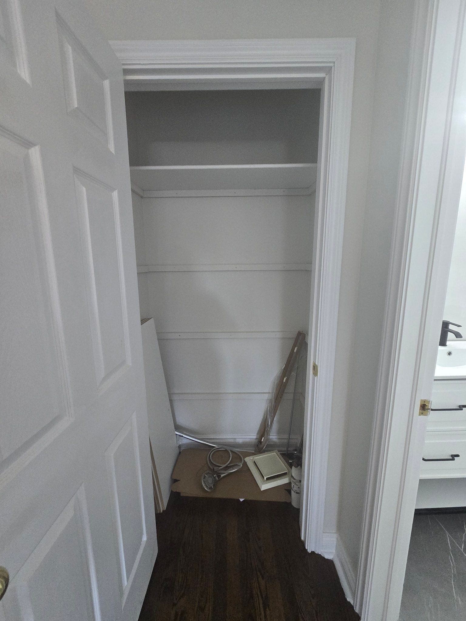 A closet with a door open and a shelf in it.