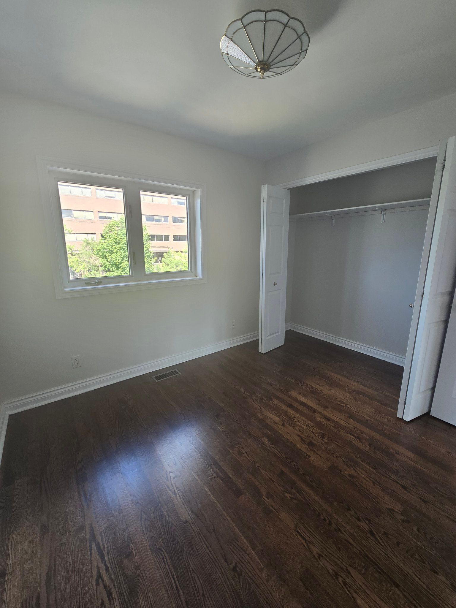 An empty bedroom with hardwood floors and a walk in closet.