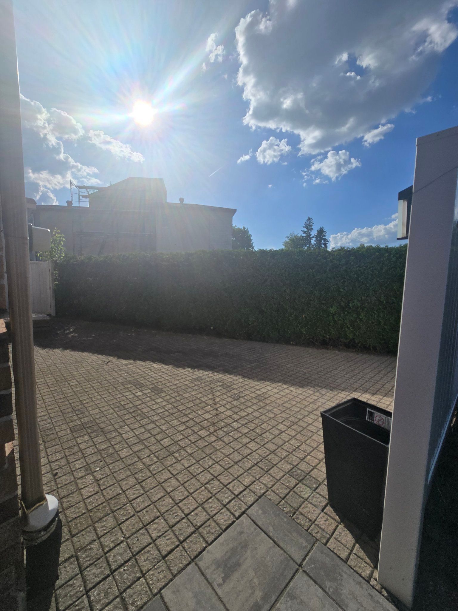 The sun is shining through the clouds over a brick driveway.