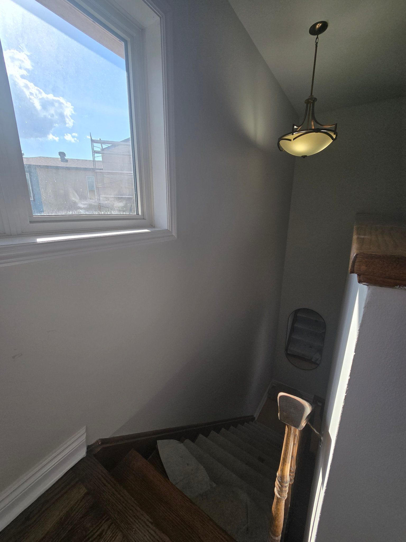 A staircase with a window and a light hanging from the ceiling.