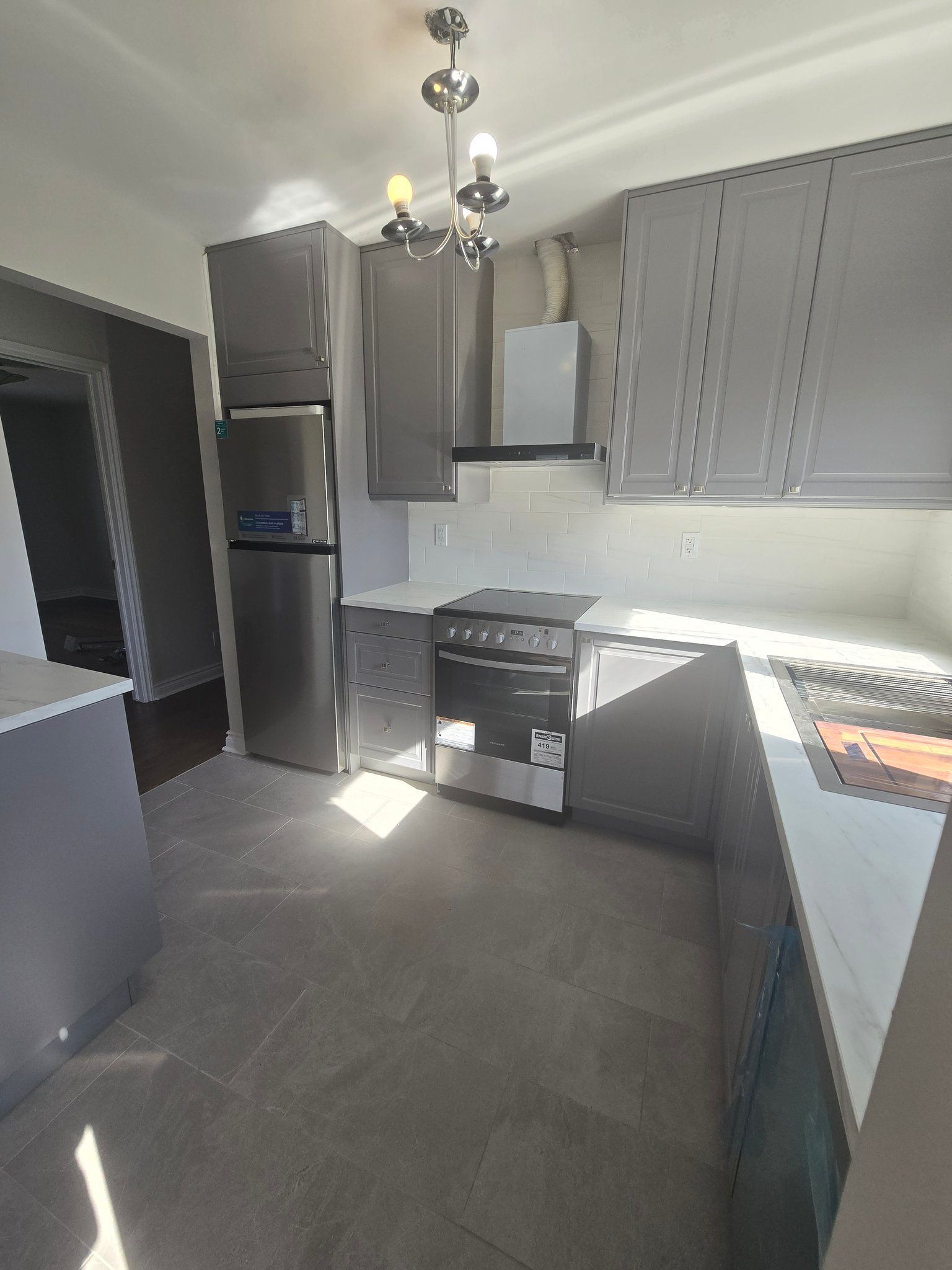 A kitchen with stainless steel appliances and gray cabinets.