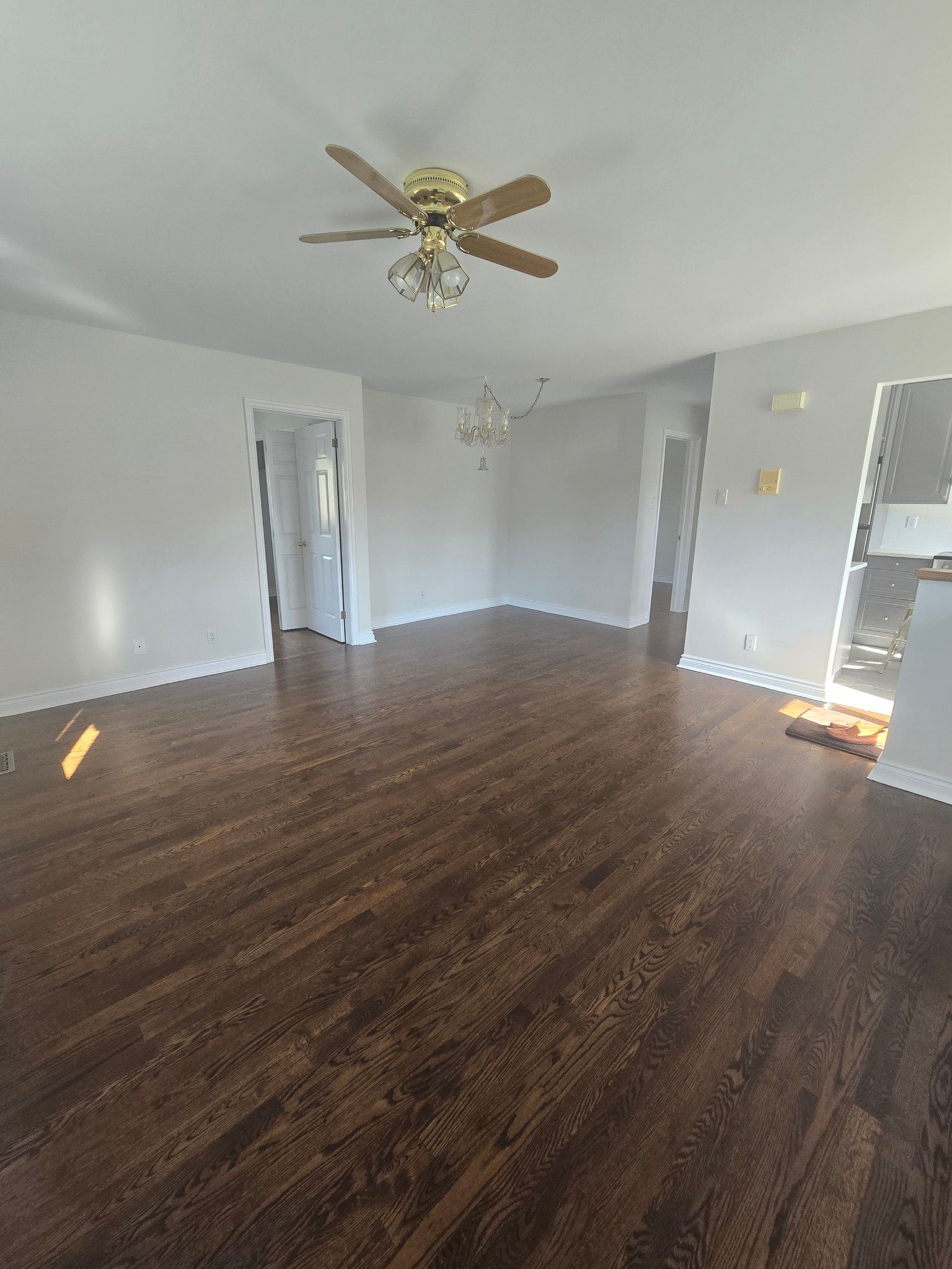 An empty living room with hardwood floors and a ceiling fan.