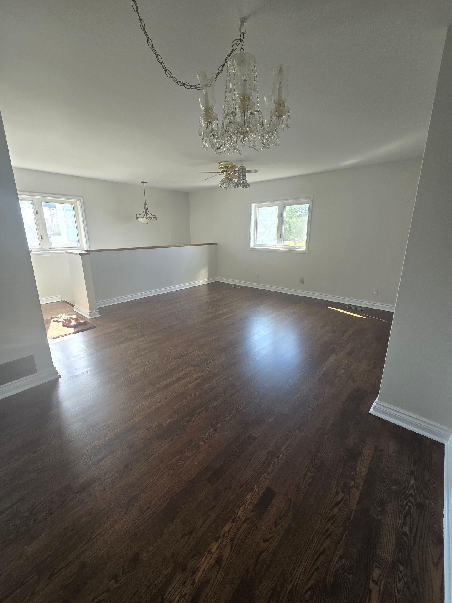A living room with hardwood floors and a chandelier hanging from the ceiling.